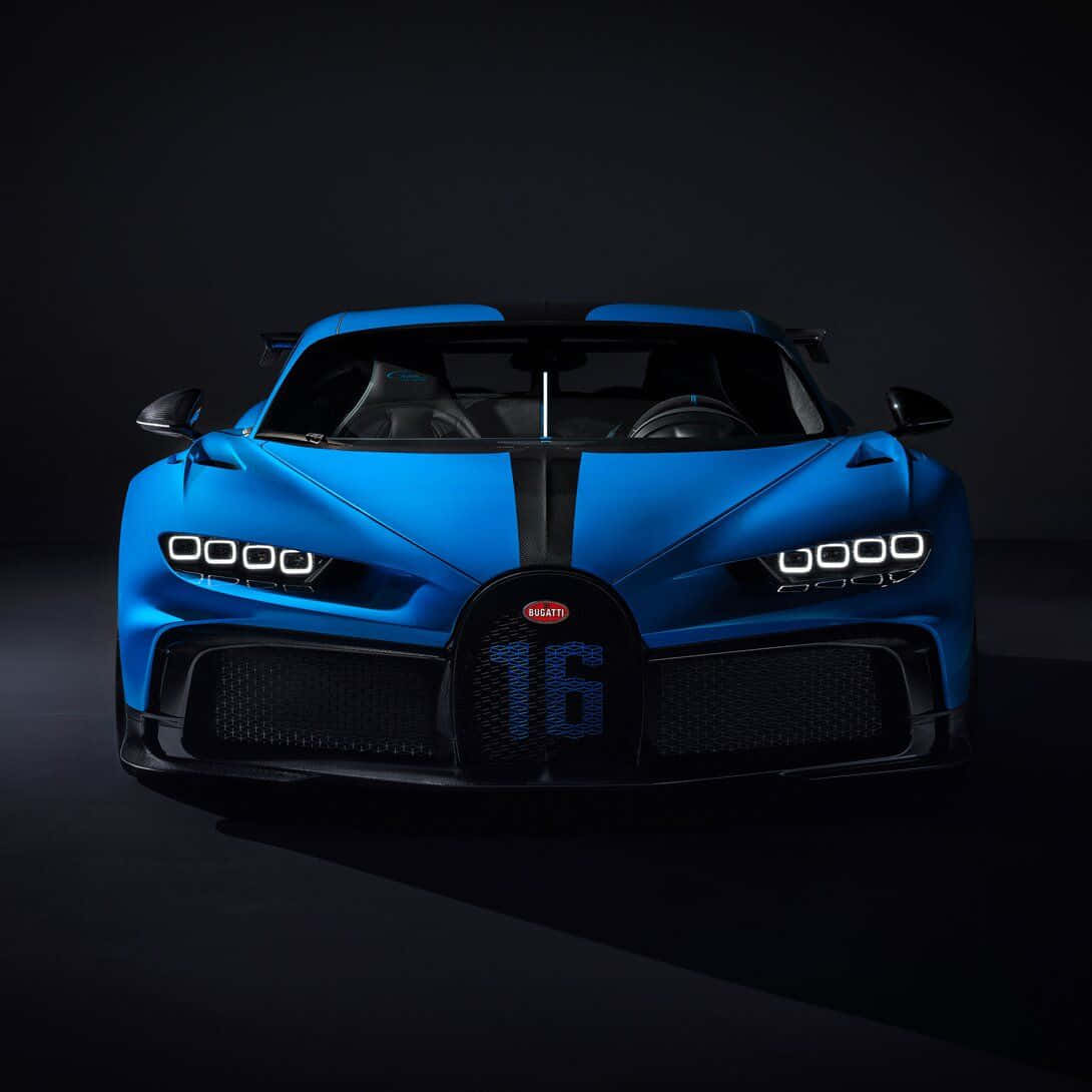 布加迪 桌布 壁紙 — 一輛引人注目的藍色Bugatti Chiron Super Sport 300+，帶有黑色飾邊和進氣格柵上的16號，在黑暗的攝影棚背景下被銳利的車頭燈照亮。