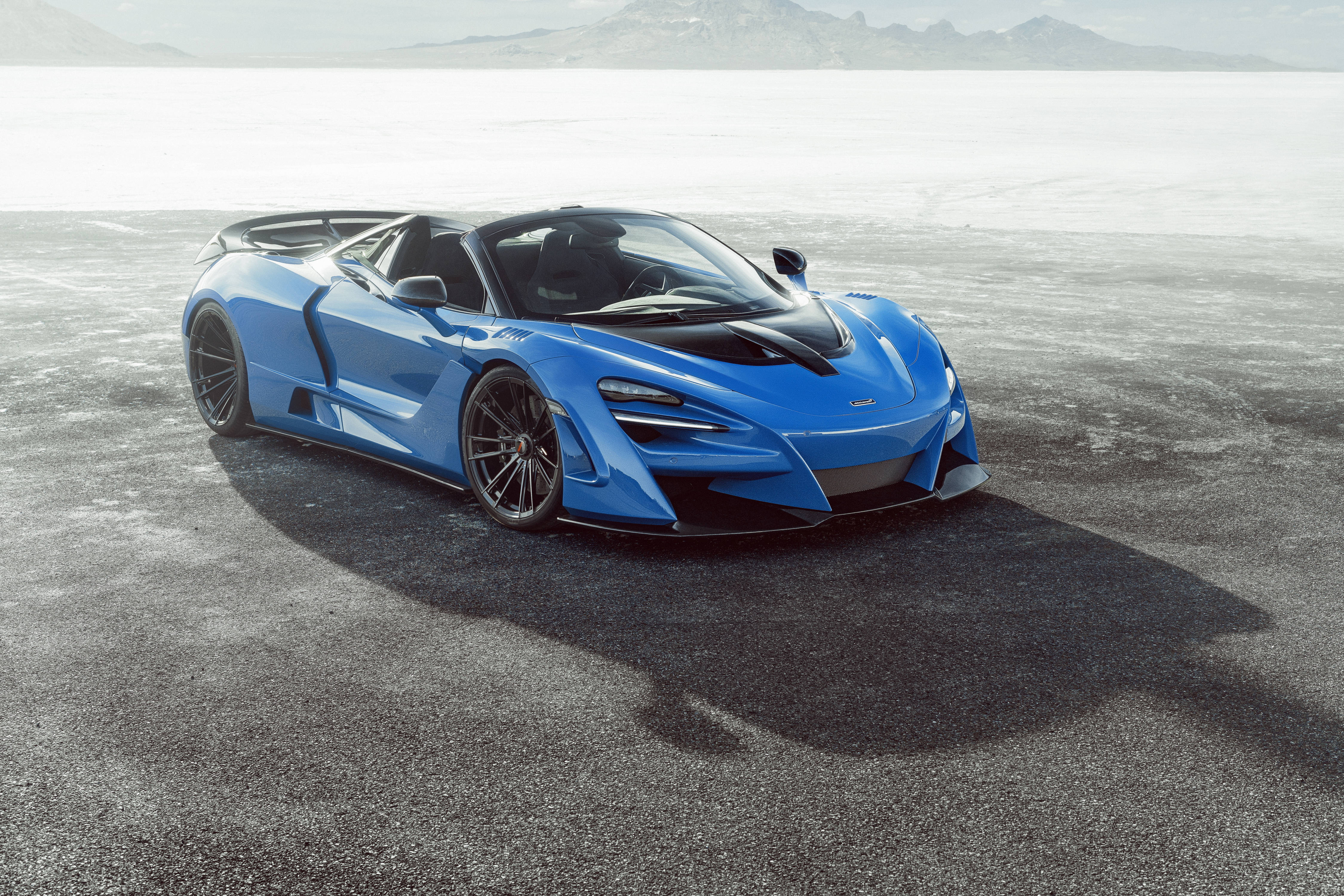 mclaren 720s 4K 桌布 壁紙 — 一輛引人注目的藍色McLaren超級跑車，帶有黑色裝飾，停在廣闊的沙漠鹽灘上，在明亮的日光下。