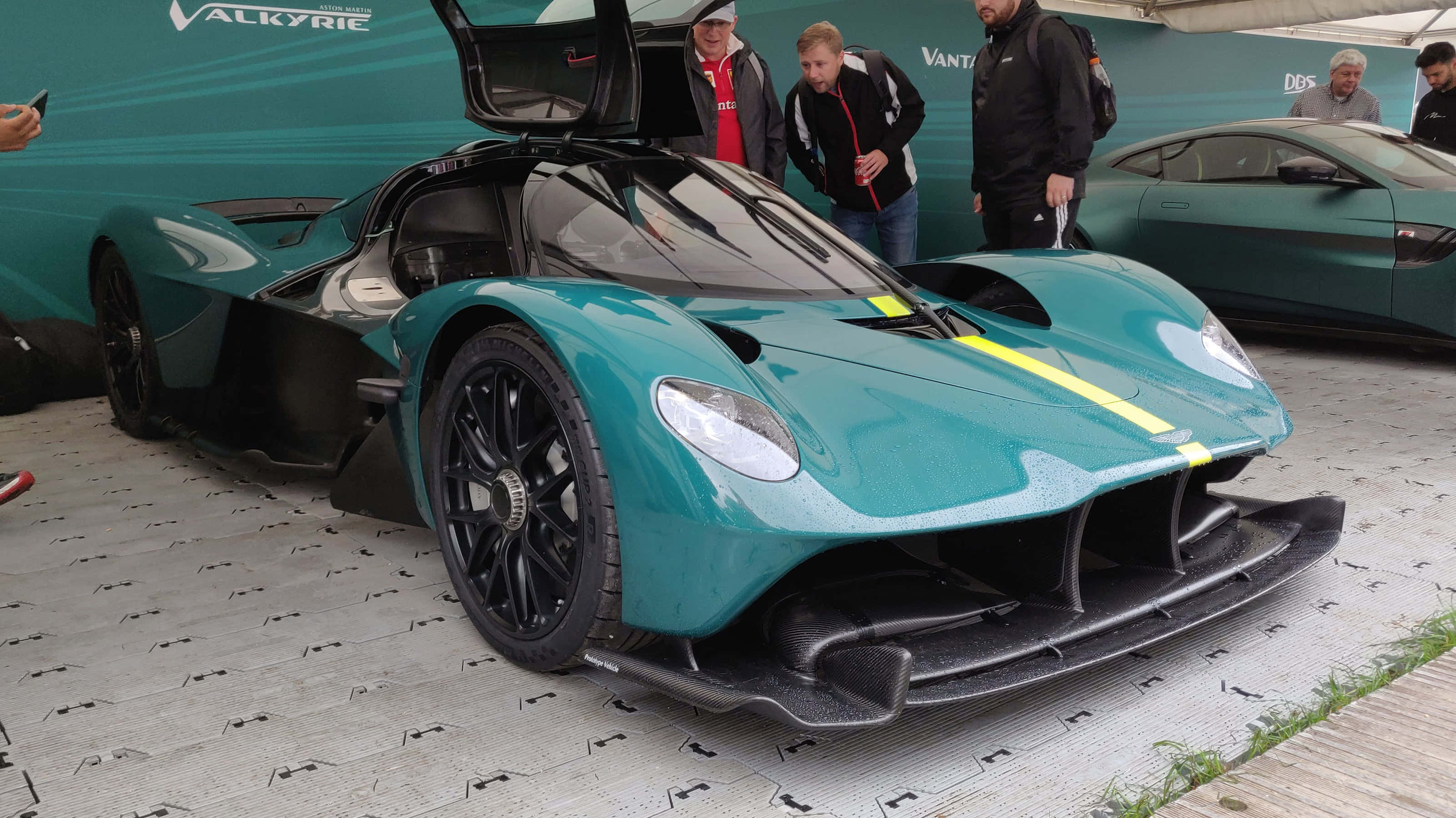 奧斯頓馬丁 桌布 壁紙 — 一輛引人注目的青綠色 Aston Martin Valkyrie 超級跑車，打開鷗翼車門在車展上展出，吸引著讚嘆的人群。