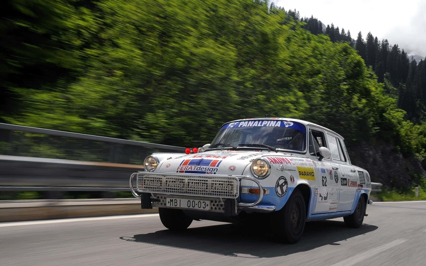 Skoda 1000 Mb 桌布 壁紙 — 一輛復古拉力賽車沿著蜿蜒的山路疾馳，茂密的綠樹模糊掠過。