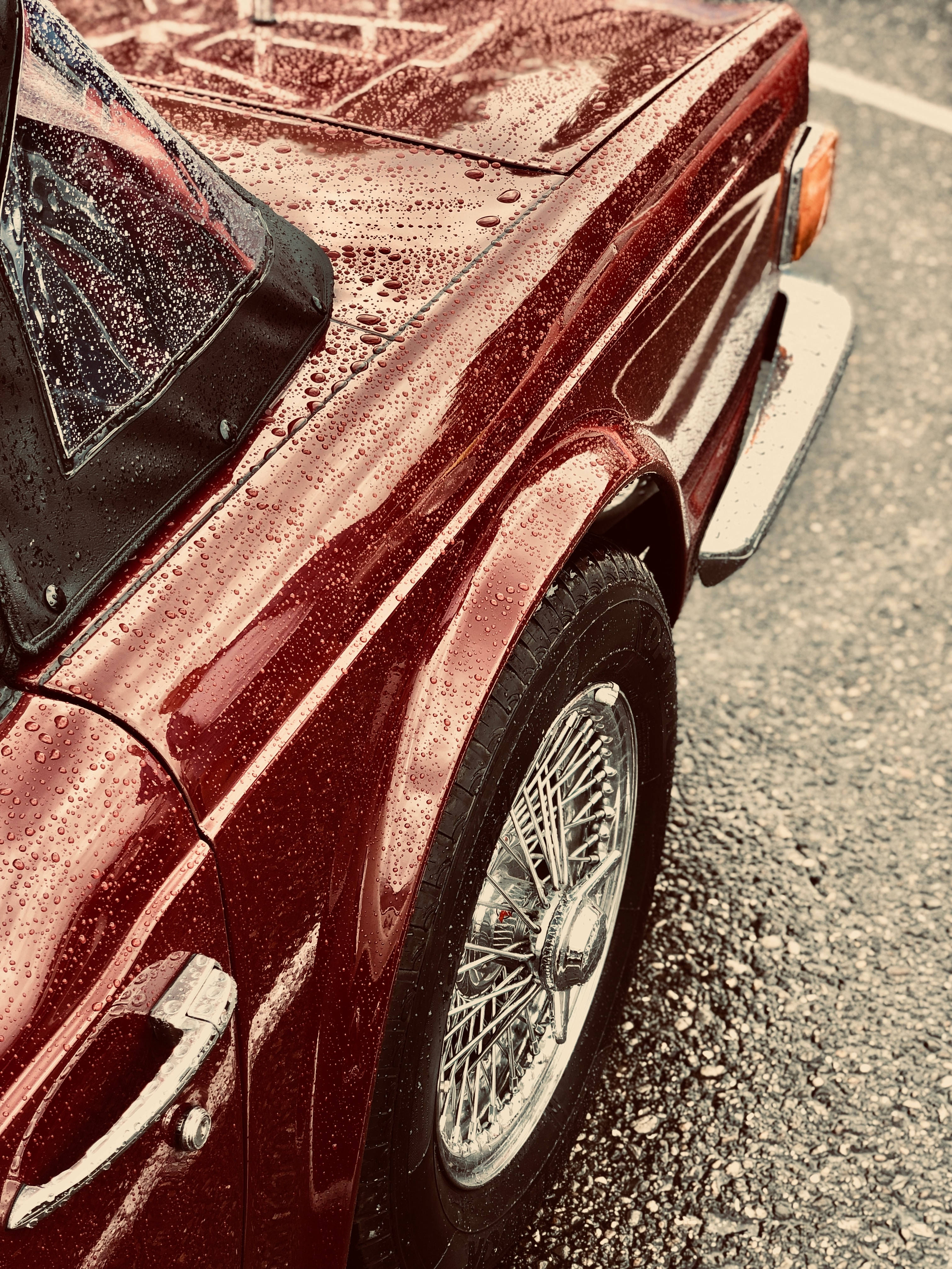 Chrome 桌布 壁紙 — 一輛復古栗色敞篷車的特寫，雨滴在光亮的引擎蓋和鋼絲輪圈上閃閃發光。
