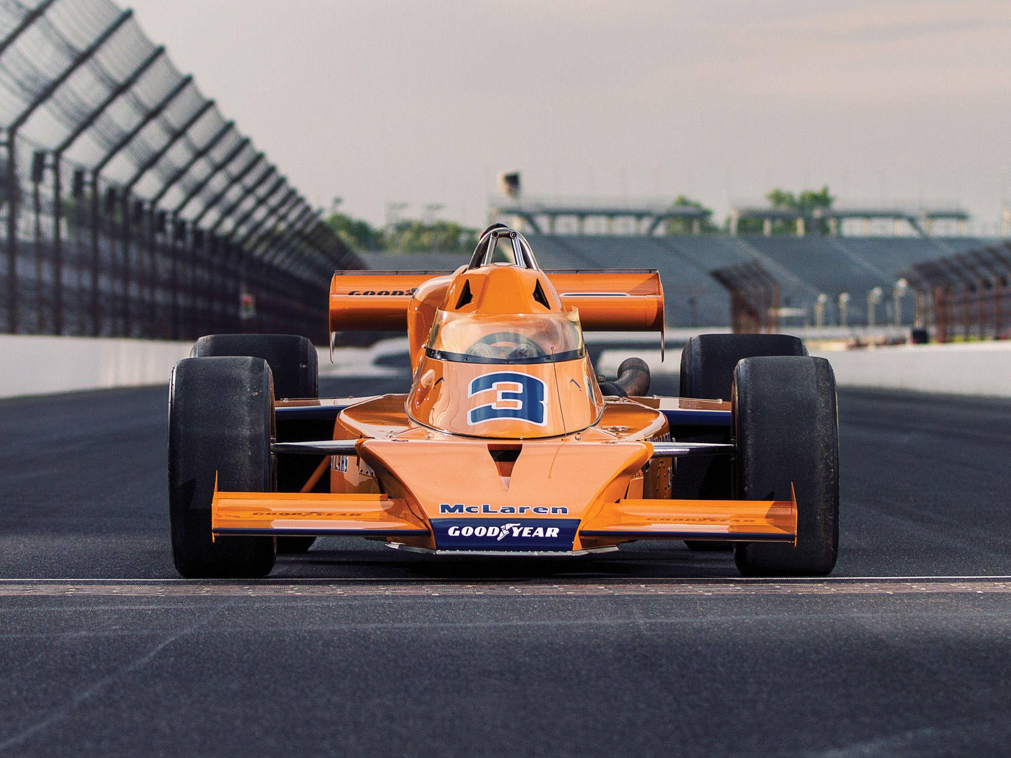 Indianapolis 桌布 壁紙 — 一輛復古橙色McLaren賽車（編號3）在朦朧的天空下於賽道上飛馳。