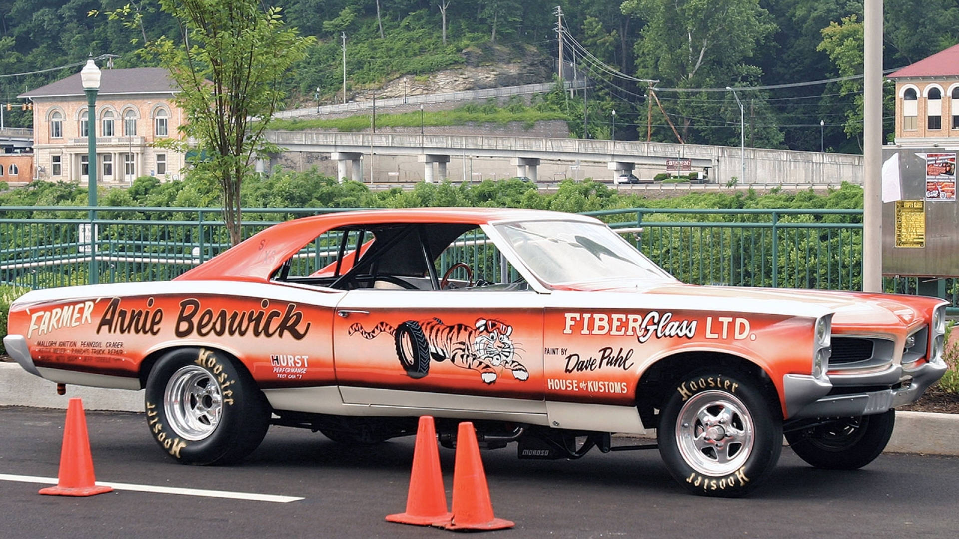Pontiac 桌布 壁紙 — 一輛復古橙色和白色的直線加速賽車，帶有老虎圖案和贊助商貼紙，停在橙色錐體附近的瀝青上。