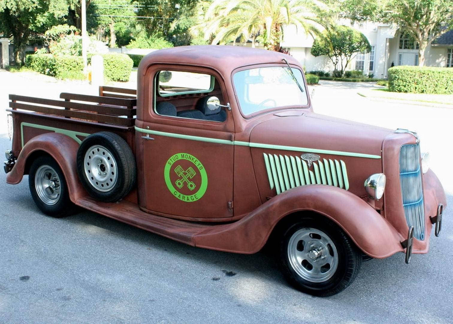 old 桌布 壁紙 — 一輛復古生鏽棕色皮卡車，帶有綠色飾邊和「Blud Monkeys Garage」標誌，停在郊區街道上。