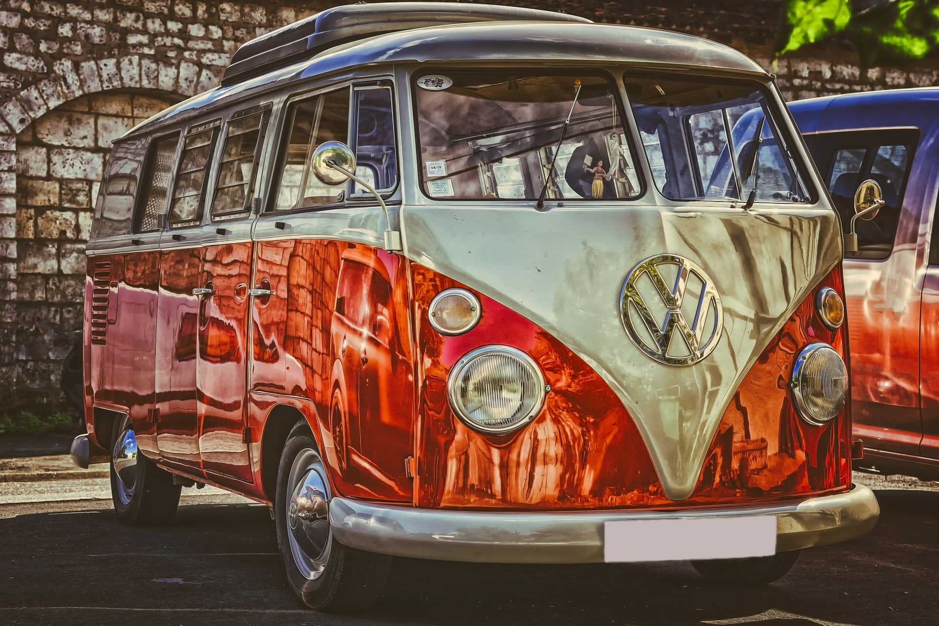 Van 桌布 壁紙 — 一輛復古紅色和奶油色的福斯 Type 2 廂型車停放在石拱門旁，帶有反光鍍鉻細節。
