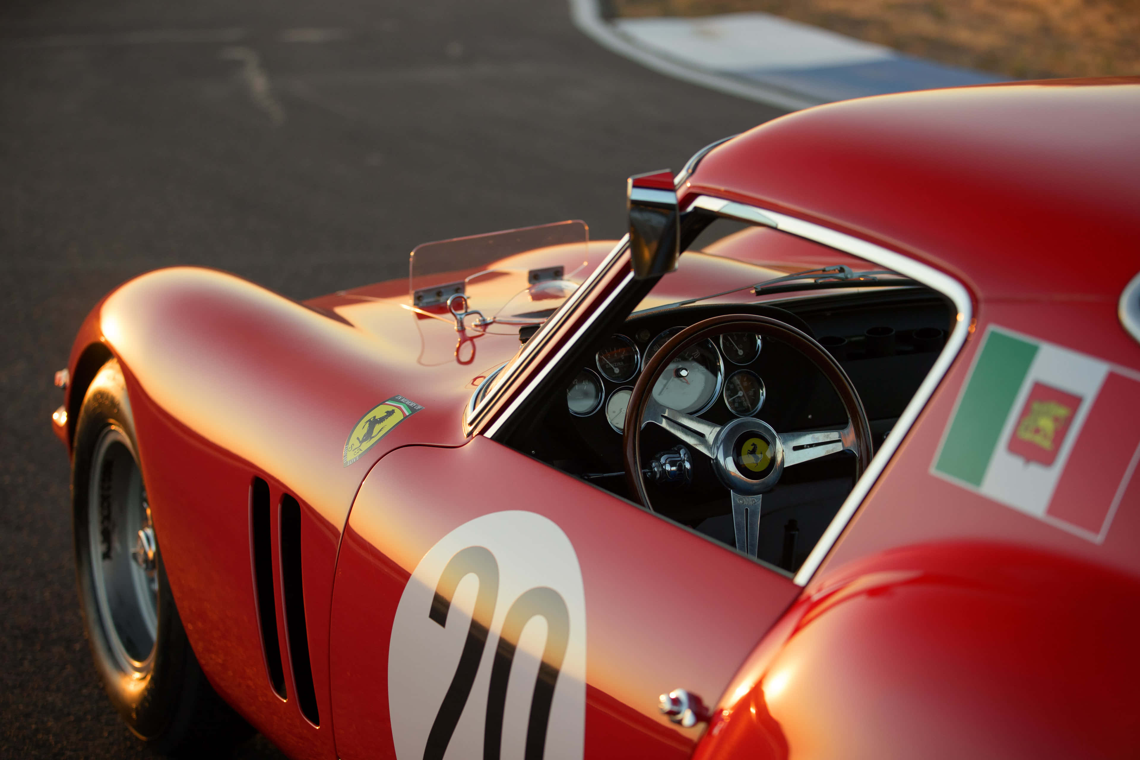 Vintage Ferrari 桌布 壁紙 — 一輛復古紅色法拉利賽車，帶有20號和葡萄牙國旗，在黃金時段的賽道上閃閃發光。