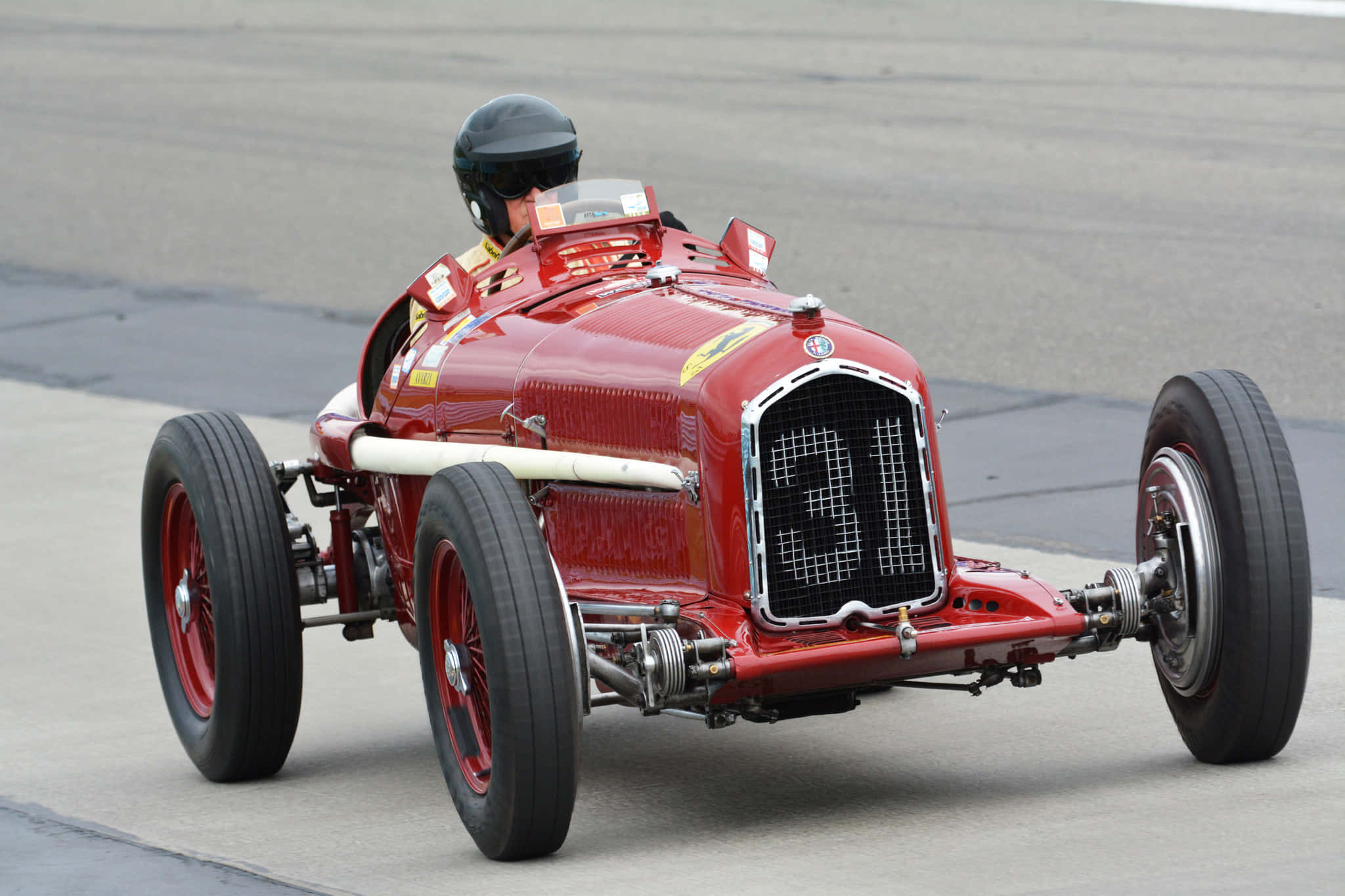 Car Racing 桌布 壁紙 — 一輛復古紅色賽車，機械結構外露，在灰色瀝青賽道上疾馳，車手戴著黑色頭盔。