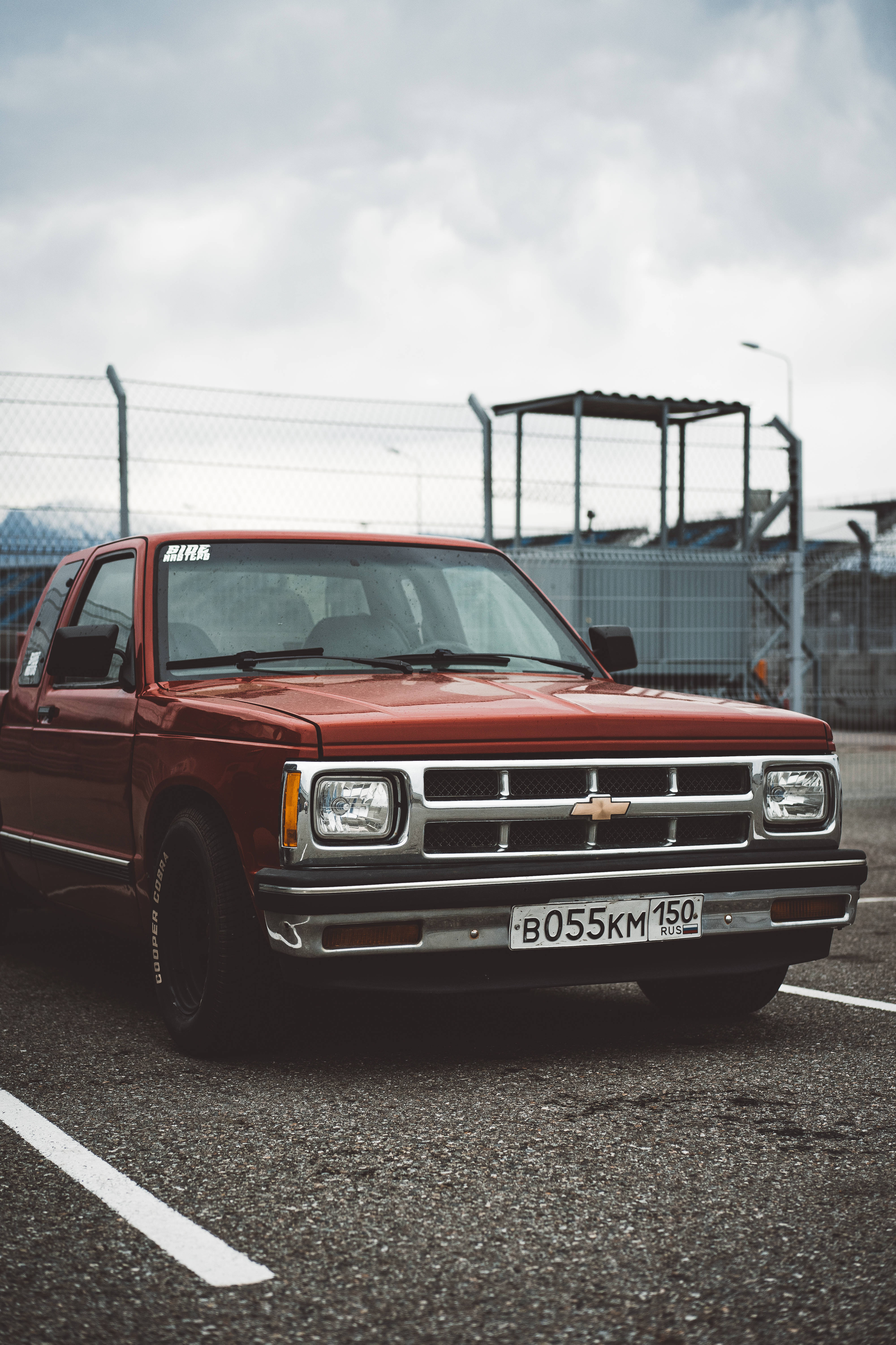 Chevrolet 桌布 壁紙 — 一輛復古紅色雪佛蘭皮卡車停在瀝青地上，天空多雲，背景有鐵絲網圍欄。