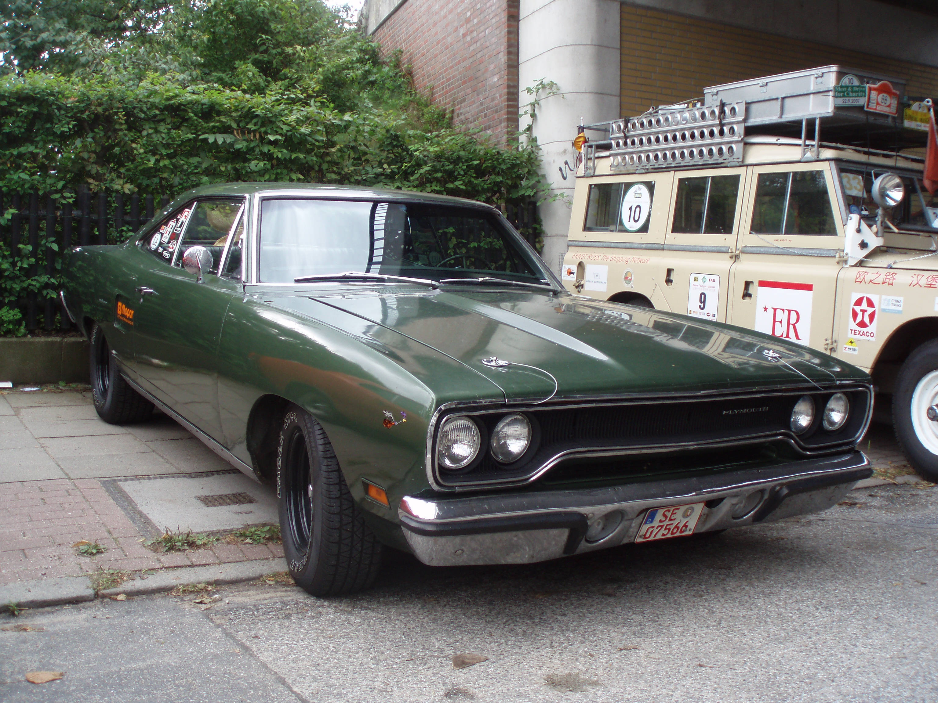 經典汽車 桌布 壁紙 — 一輛復古綠色Dodge Dart肌肉車停放在人行道上，旁邊是一輛帶有賽車貼紙的米色賽車卡車。