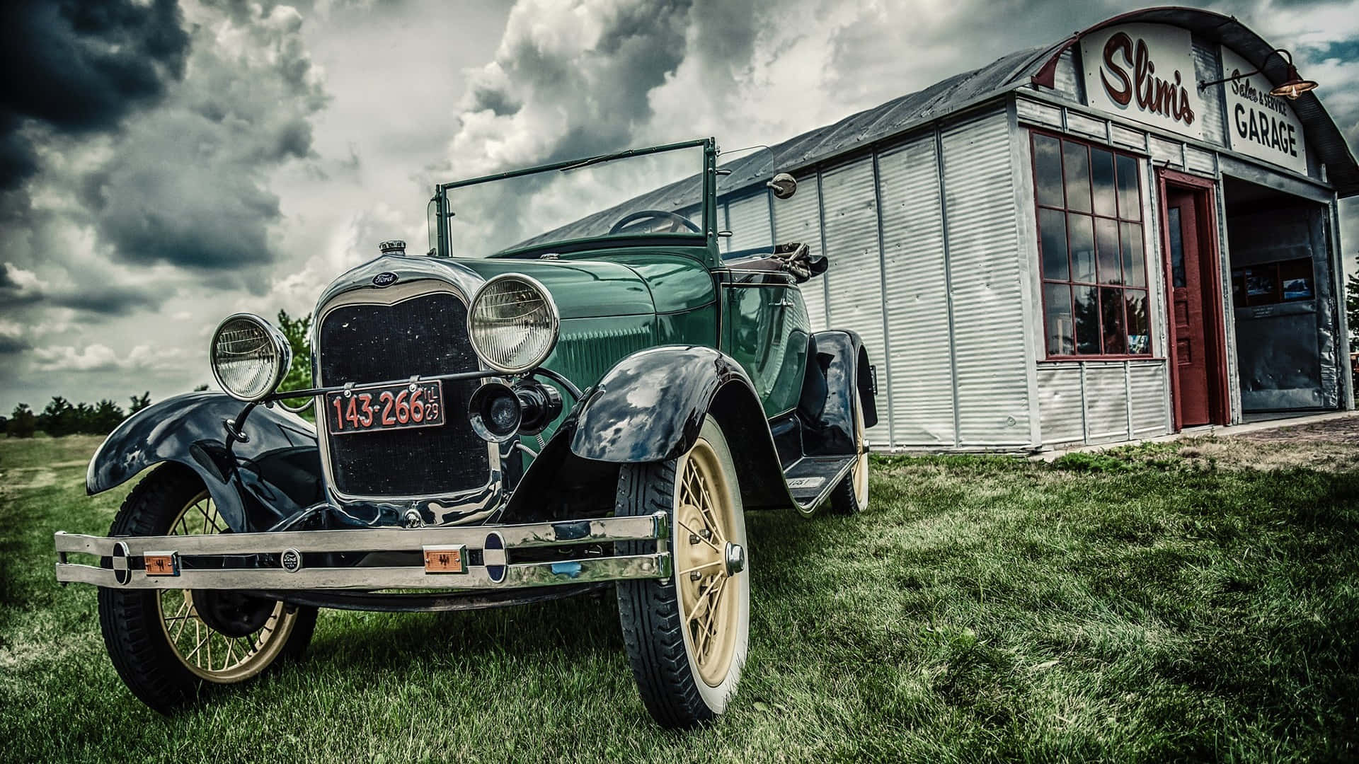 Vintage Car 桌布 壁紙 — 一輛復古綠色福特 Model T 停在草地上，前方是飽經風霜的波紋金屬車庫，上方是戲劇性的暴風雲。