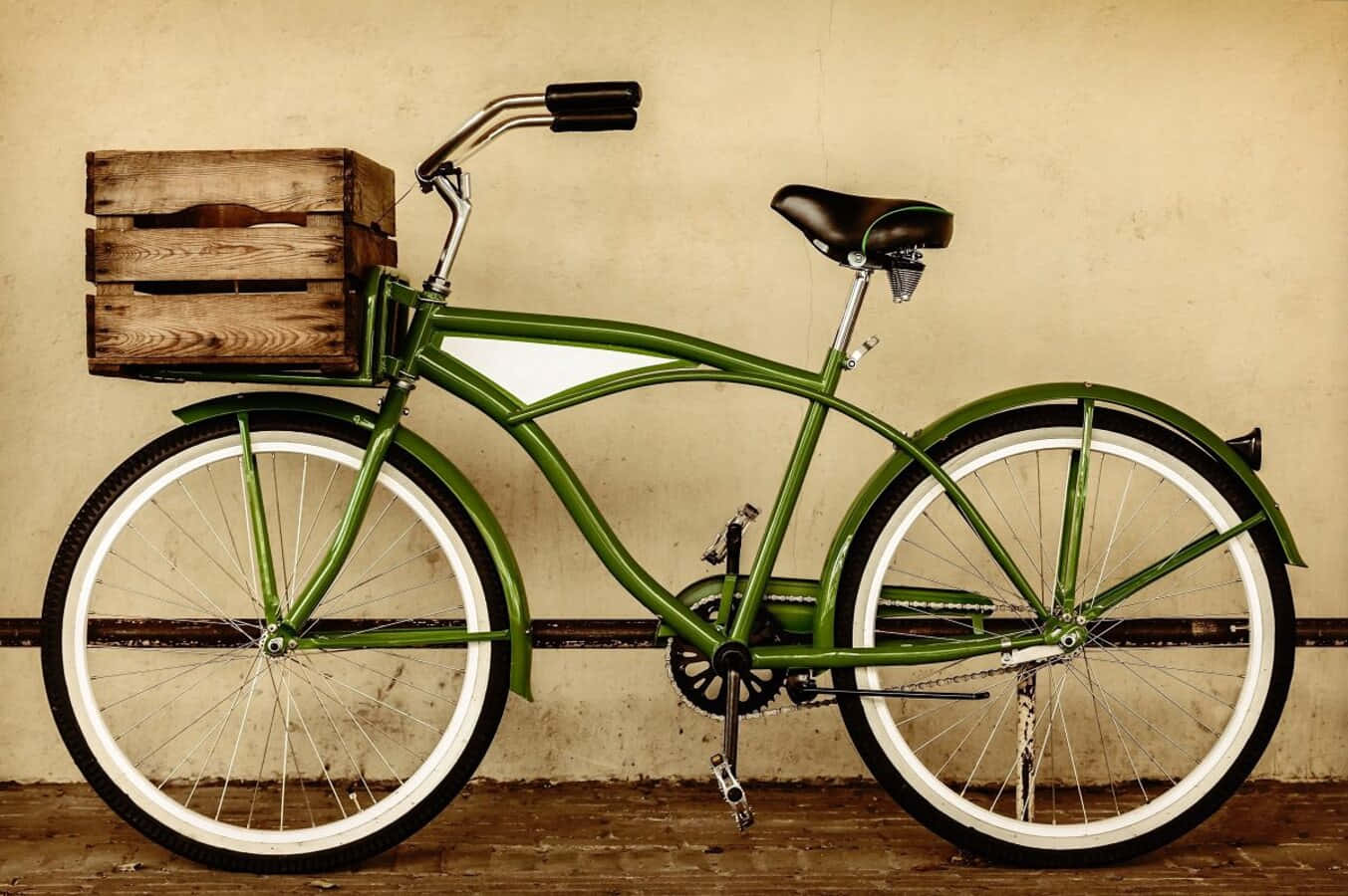 Beach Cruiser 桌布 壁紙 — 一輛復古綠色自行車，配有白邊輪胎和前面的木箱，靠在一面有紋理的米色牆上。