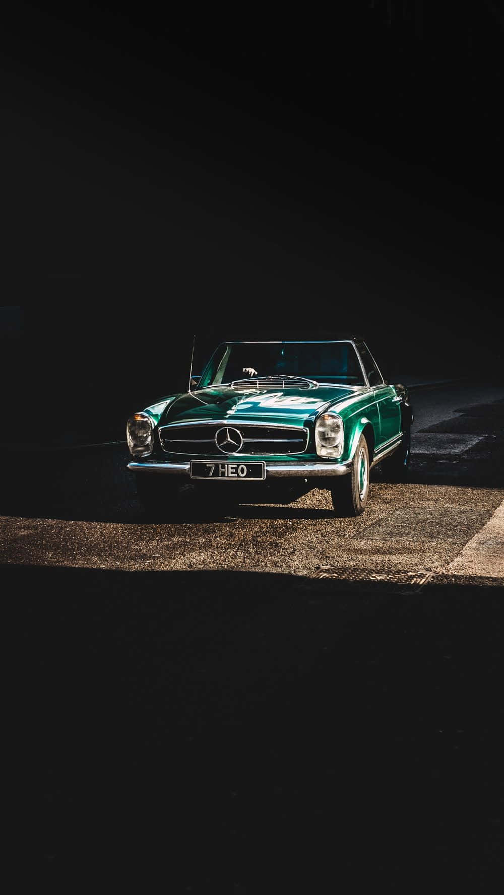 Classic Mercedes 桌布 壁紙 — 一輛復古綠色賓士SL停泊在碎石路上，在黑暗背景下被戲劇性的聚光燈照射。