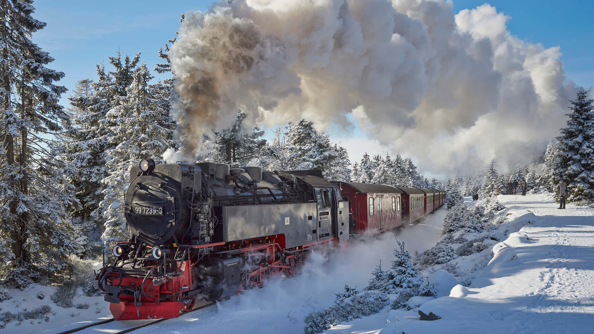 Hogwarts Express 桌布 壁紙 — 一輛復古蒸汽火車穿過白雪覆蓋的森林，向清澈的藍天噴出濃煙。