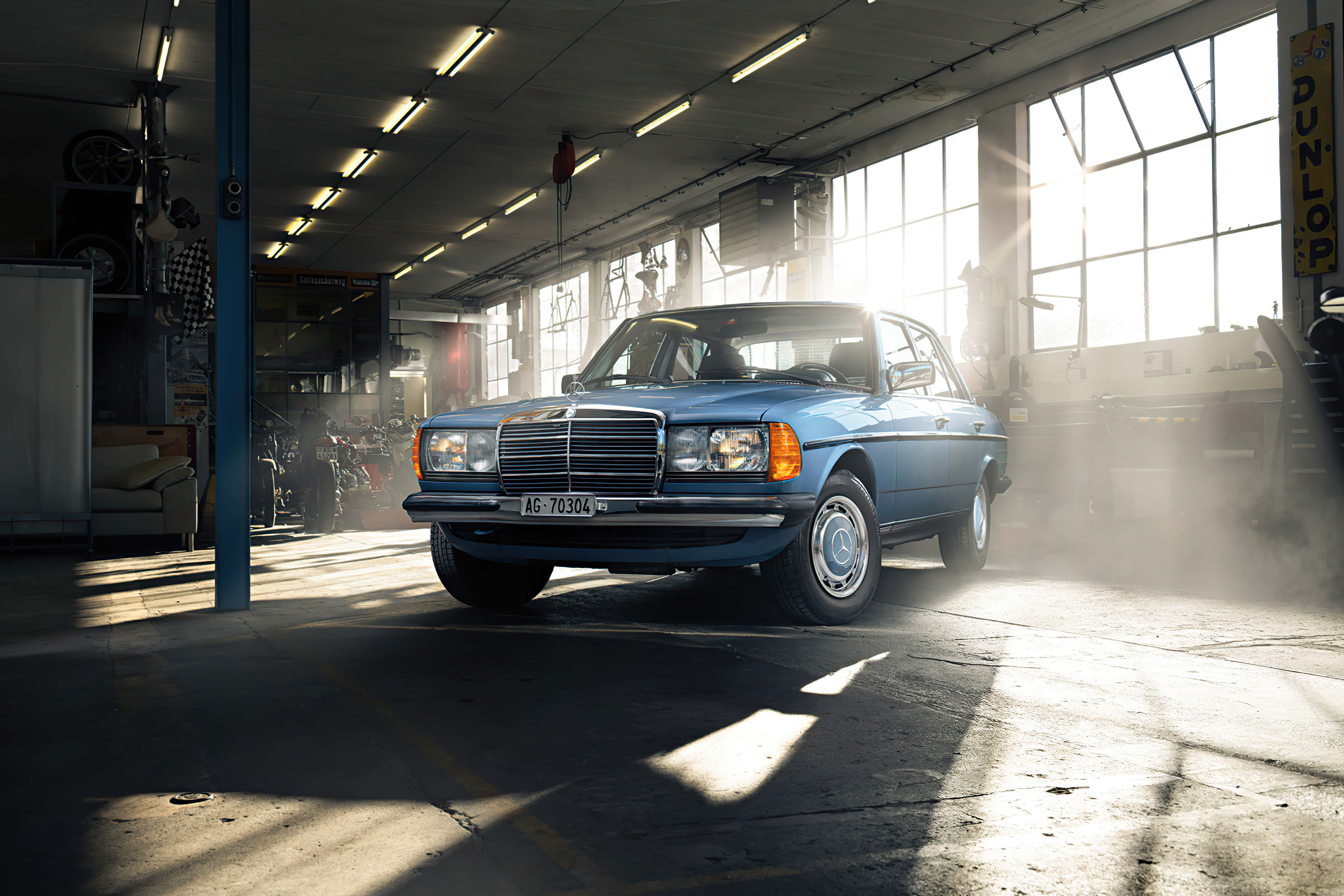Classic Mercedes 桌布 壁紙 — 一輛復古藍色 Mercedes-Benz 房車停在陽光充足的車庫中，灰塵在大窗戶射入的光束中舞動。