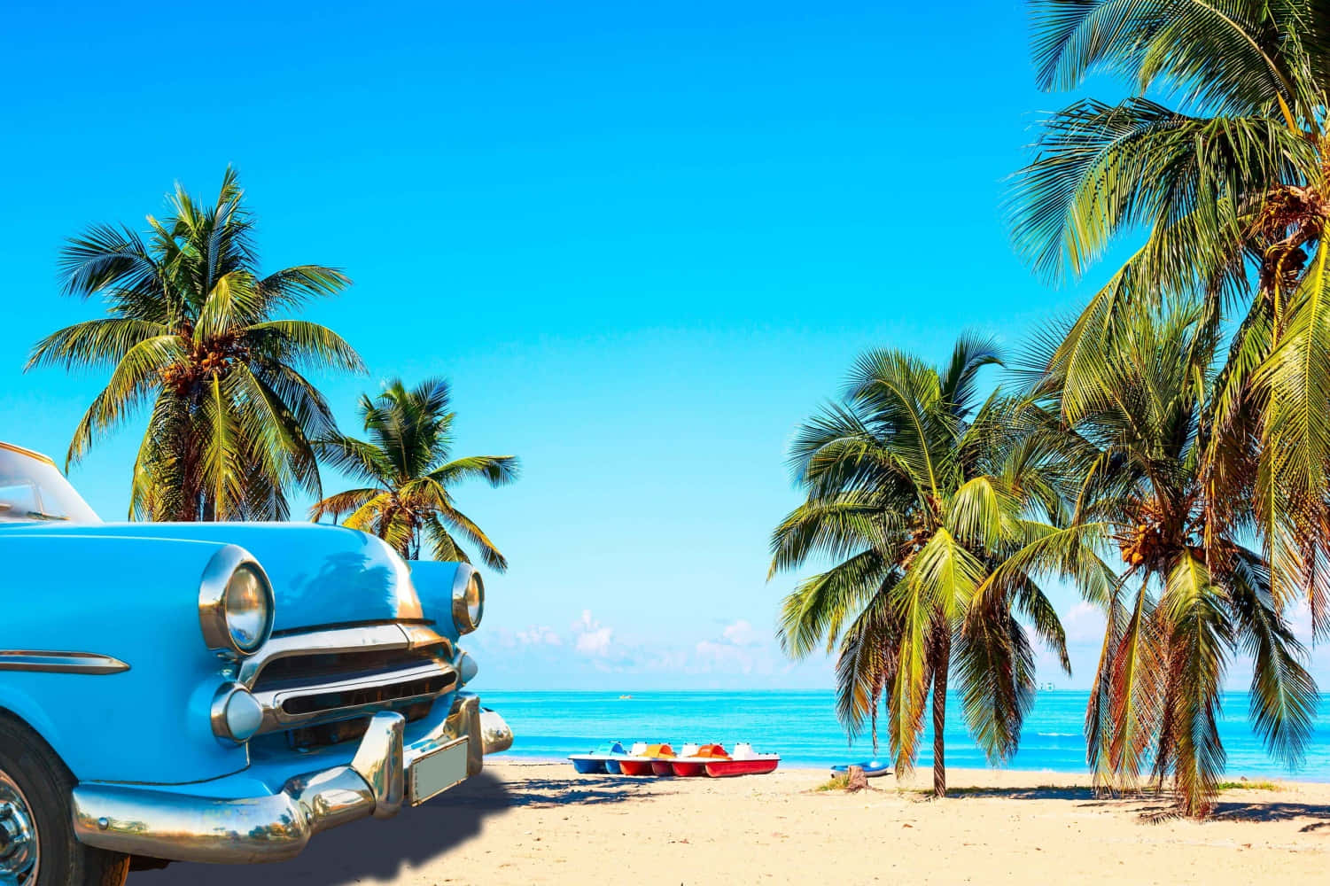 Cuba 桌布 壁紙 — 一輛復古藍色汽車停放在陽光明媚的海灘上，有棕櫚樹和碧綠的海洋，在清澈的藍天下。