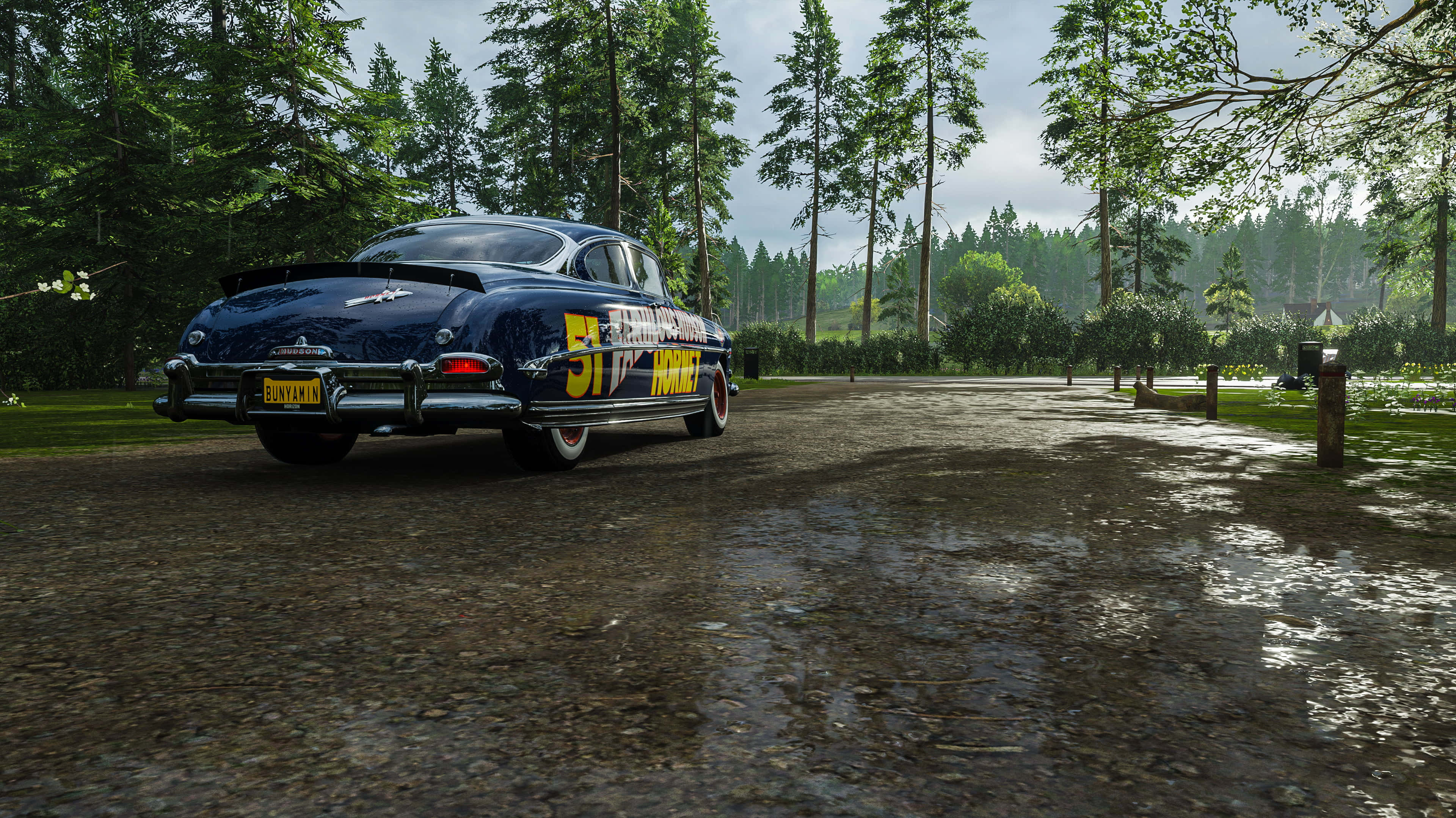Forza Horizon 5 4K 桌布 壁紙 — 一輛復古藍色賽車，帶有黃色51號，停泊在潮濕的森林道路上，天空多雲。