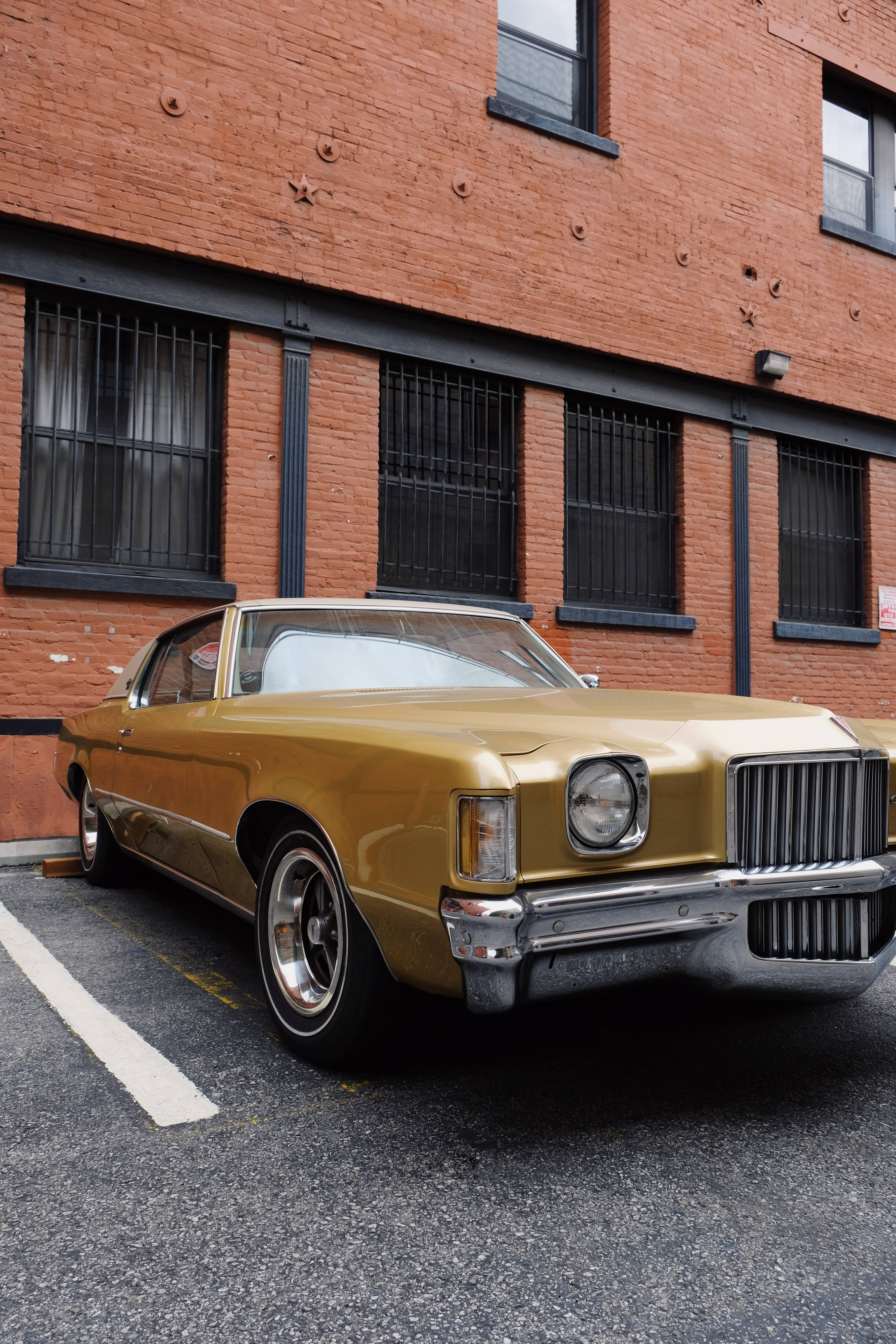 Pontiac 桌布 壁紙 — 一輛復古金色肌肉車停在風化的磚造建築前，窗戶有鐵欄杆。