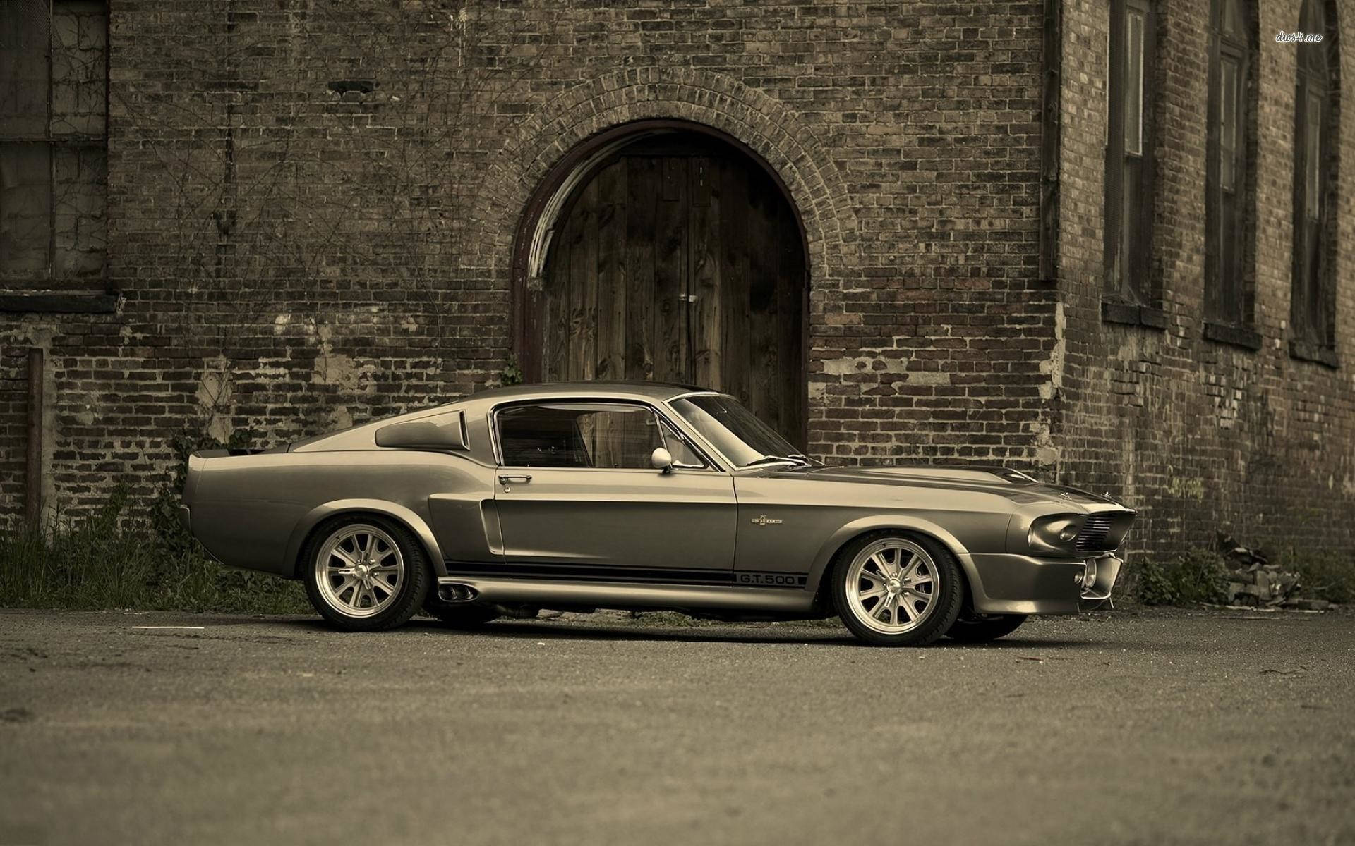 mustang HD 桌布 壁紙 — 一輛復古銀色Shelby GT350肌肉車停放在風化磚砌建築前，建築物有一道拱形木門。