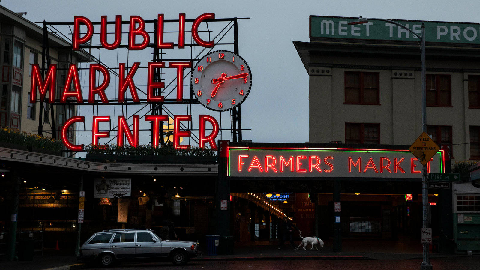 Pike Place Market 桌布 壁紙 — 一輛復古銀色旅行車在黃昏時停泊在Public Market Center和Farmers Market的紅色霓虹燈招牌下。