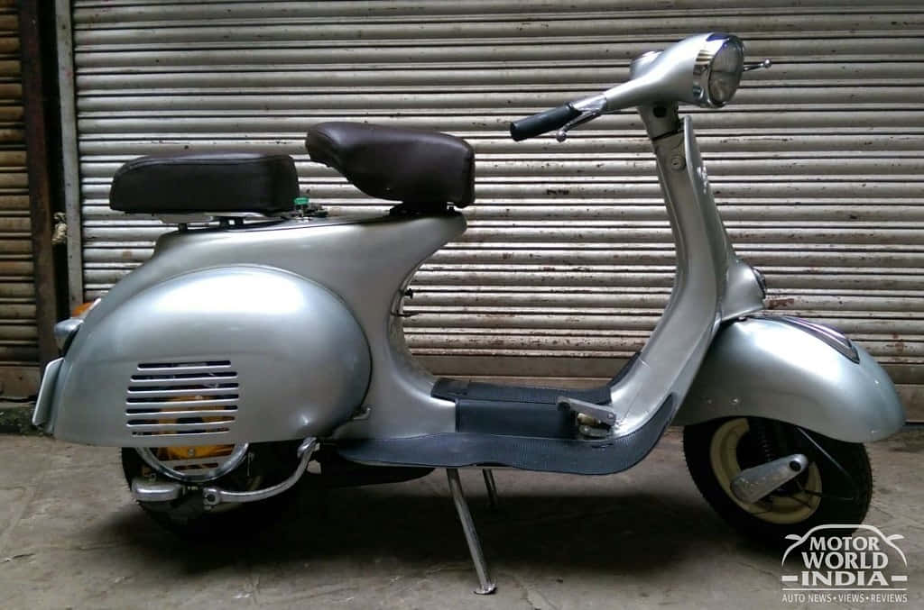 scooter 桌布 壁紙 — 一輛復古銀色機車，黑色座椅，停放在風化的金屬百葉窗前。