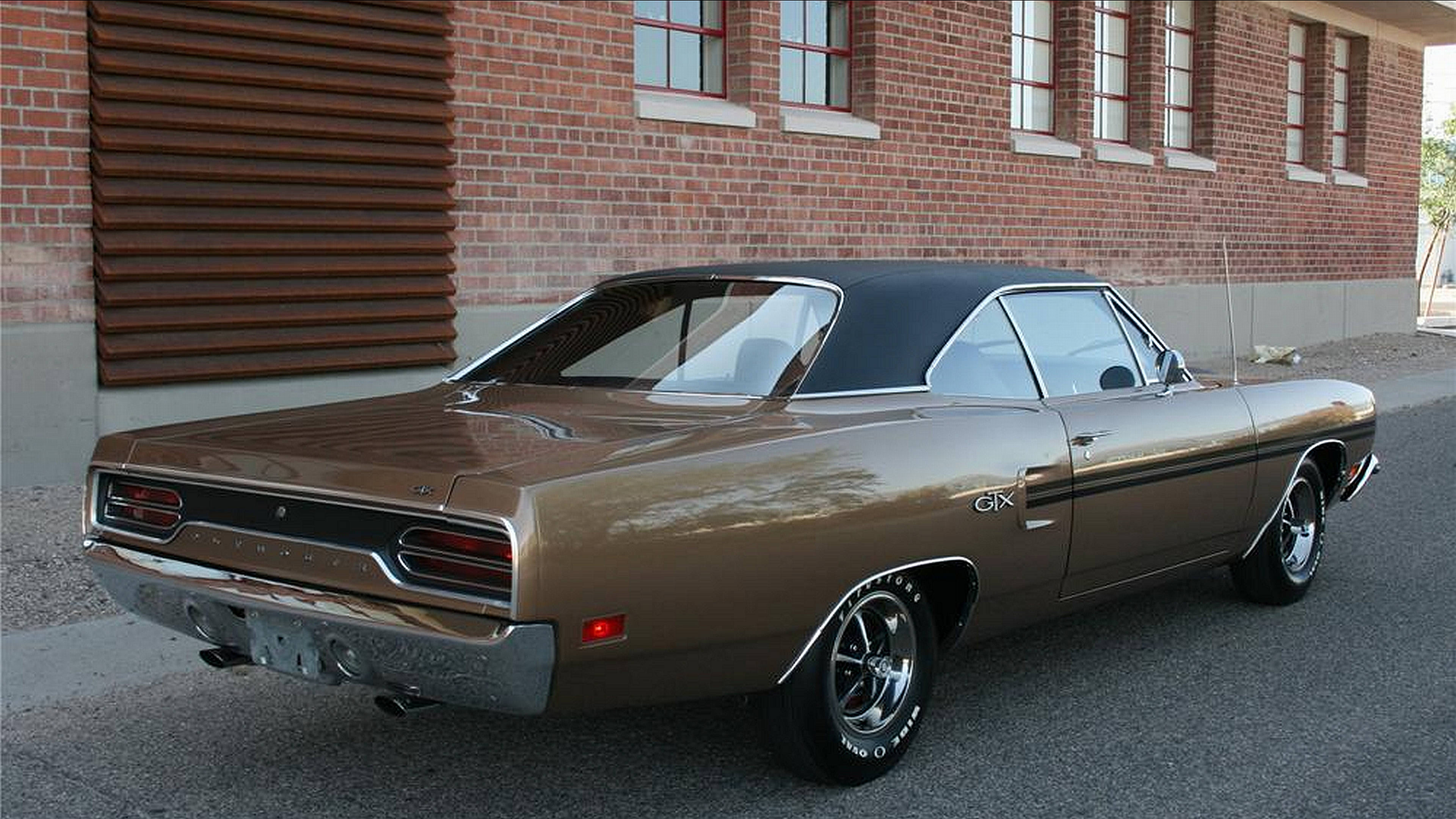 經典汽車 桌布 壁紙 — 一輛復古青銅色Dodge Charger GTX，黑色乙烯基車頂，停在紅磚建築旁的瀝青路面上。