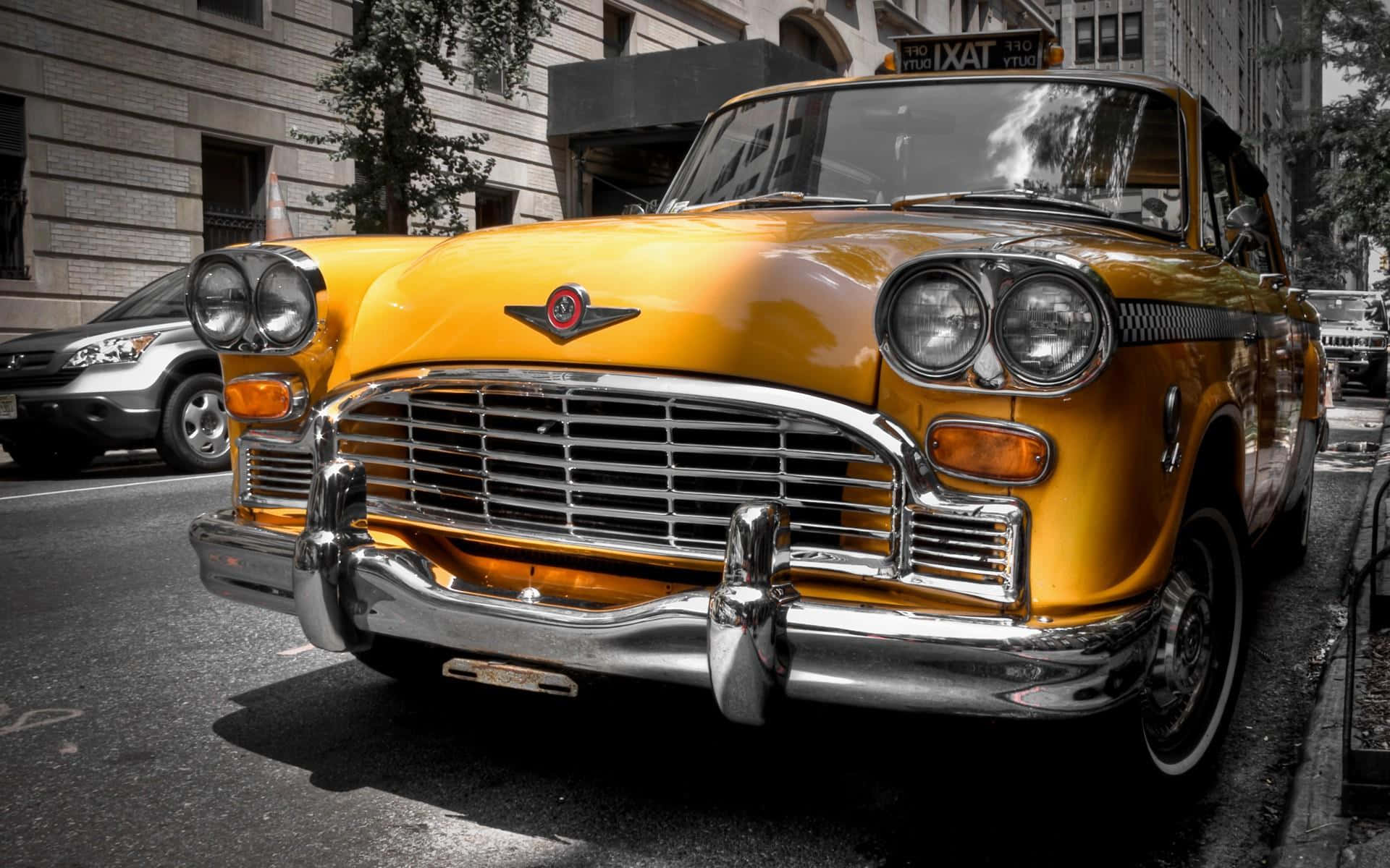 Yellow Car 桌布 壁紙 — 一輛復古黃色計程車帶有鍍鉻細節，在明亮的日光下停泊在城市街道上。