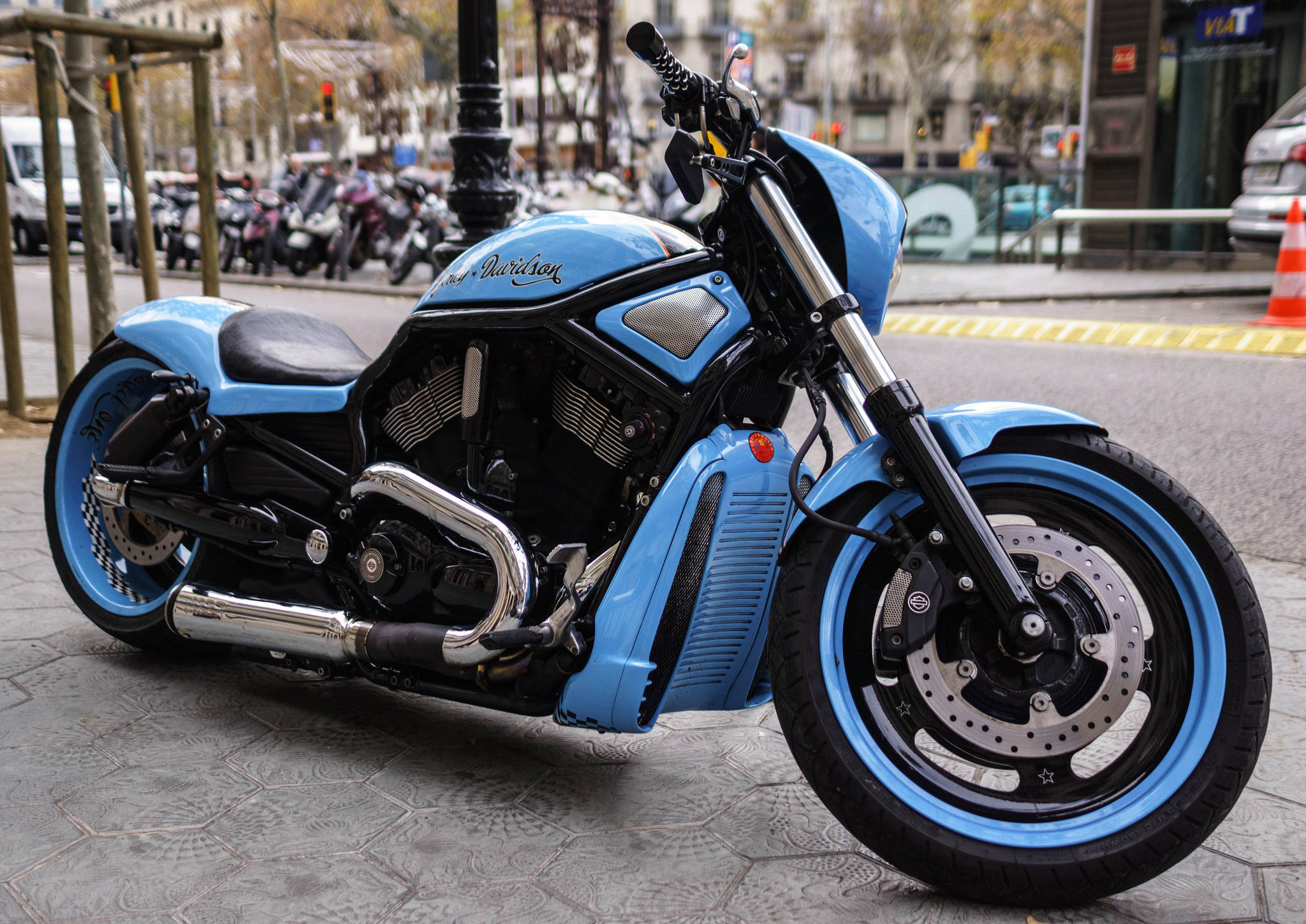 Harley 桌布 壁紙 — 一輛搶眼的淺藍色Harley-Davidson機車，帶有鍍鉻裝飾，停放在城市人行道上。