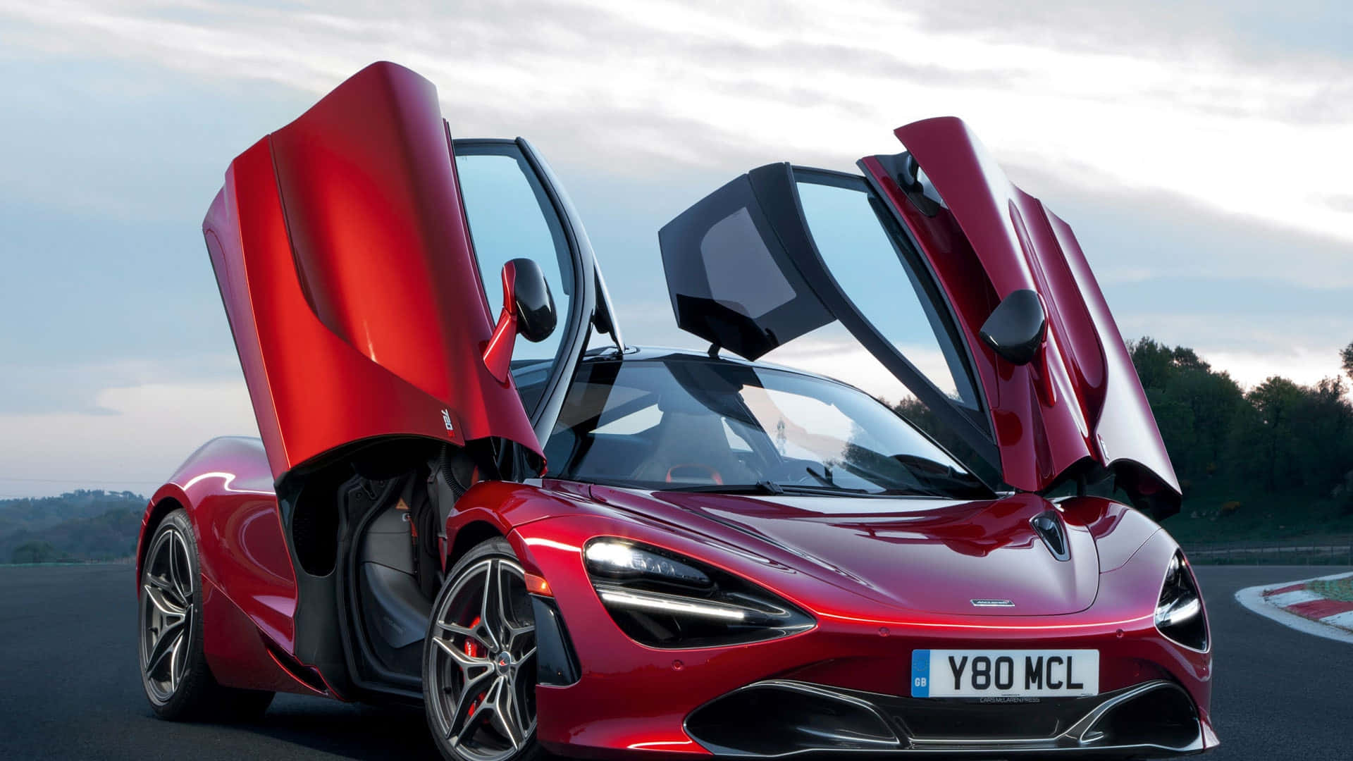 Race Track 桌布 壁紙 — 一輛搶眼的紅色McLaren 720S超級跑車，在黃昏的賽道上打開鷗翼車門。