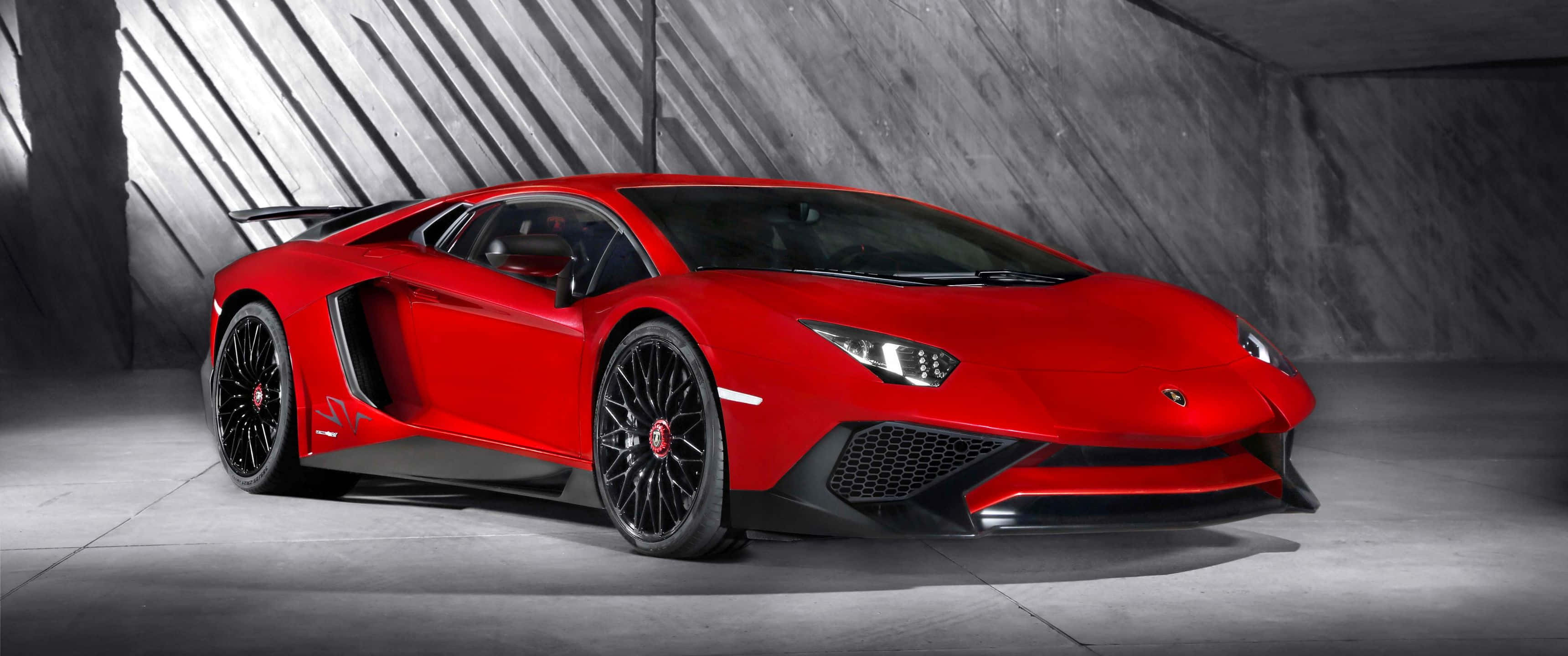 豪華車 桌布 壁紙 — 一輛搶眼的紅色藍寶堅尼 Aventador SVJ 在時尚的混凝土車庫中，在戲劇性的燈光下閃閃發光。