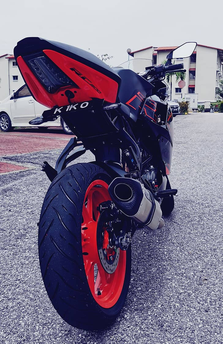 KTM RC 200 桌布 壁紙 — 一輛搶眼的紅黑色運動機車停在柏油路上，背景是住宅建築。