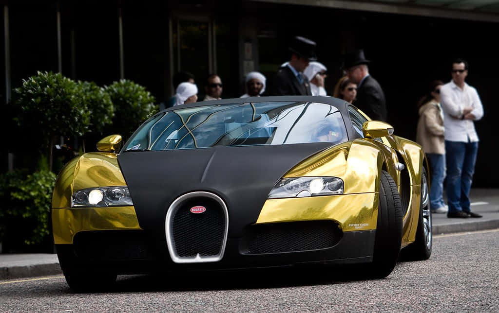 布加迪 桌布 壁紙 — 一輛搶眼的金色和黑色Bugatti Veyron跑車在日光下閃閃發光，旁觀者聚集在附近。