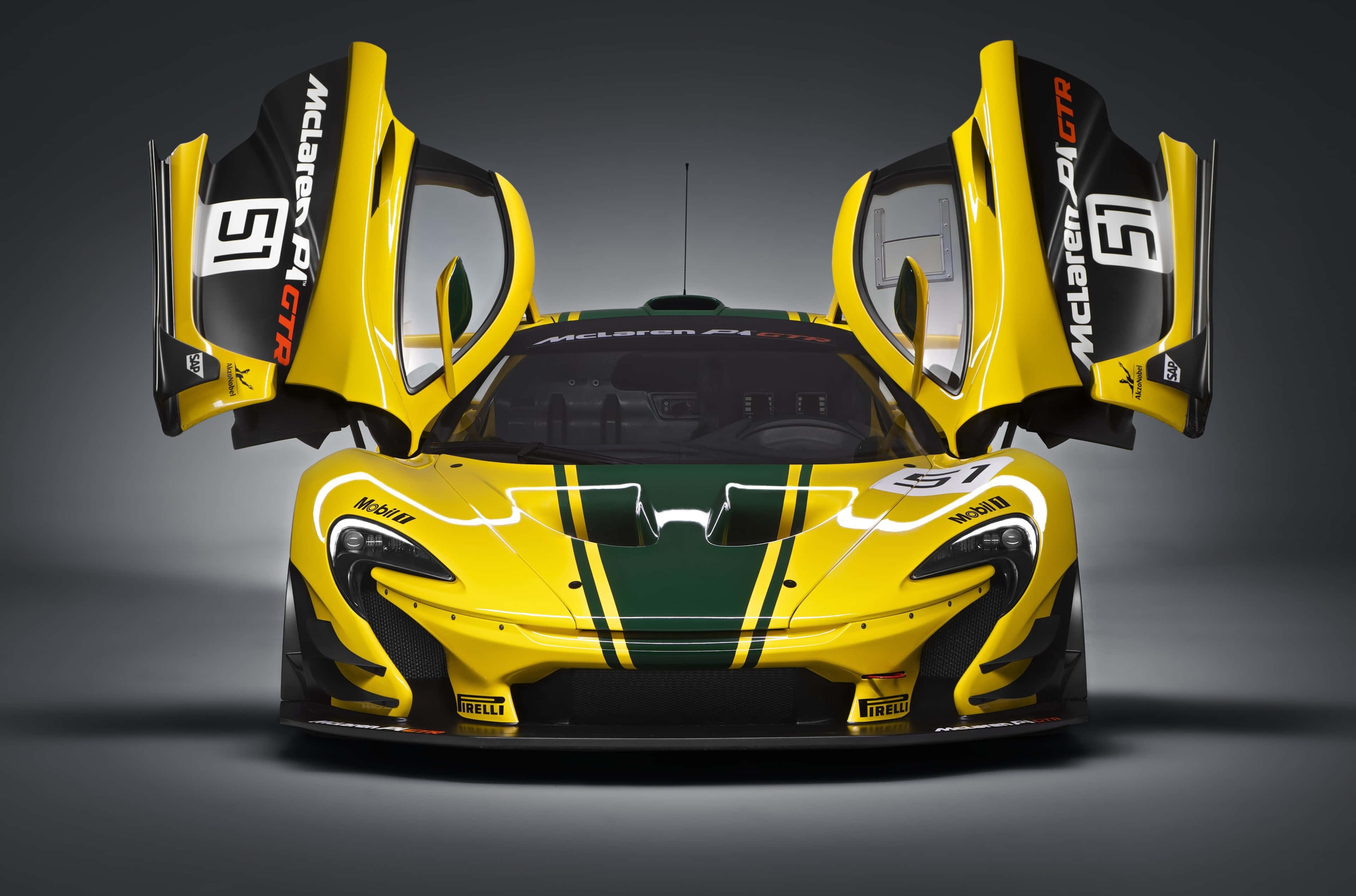 Cool Mclaren 桌布 壁紙 — 一輛搶眼的黃色McLaren P1 GTR賽車，打開蝴蝶門，帶有綠色賽車條紋，在深色攝影棚背景下擺拍。