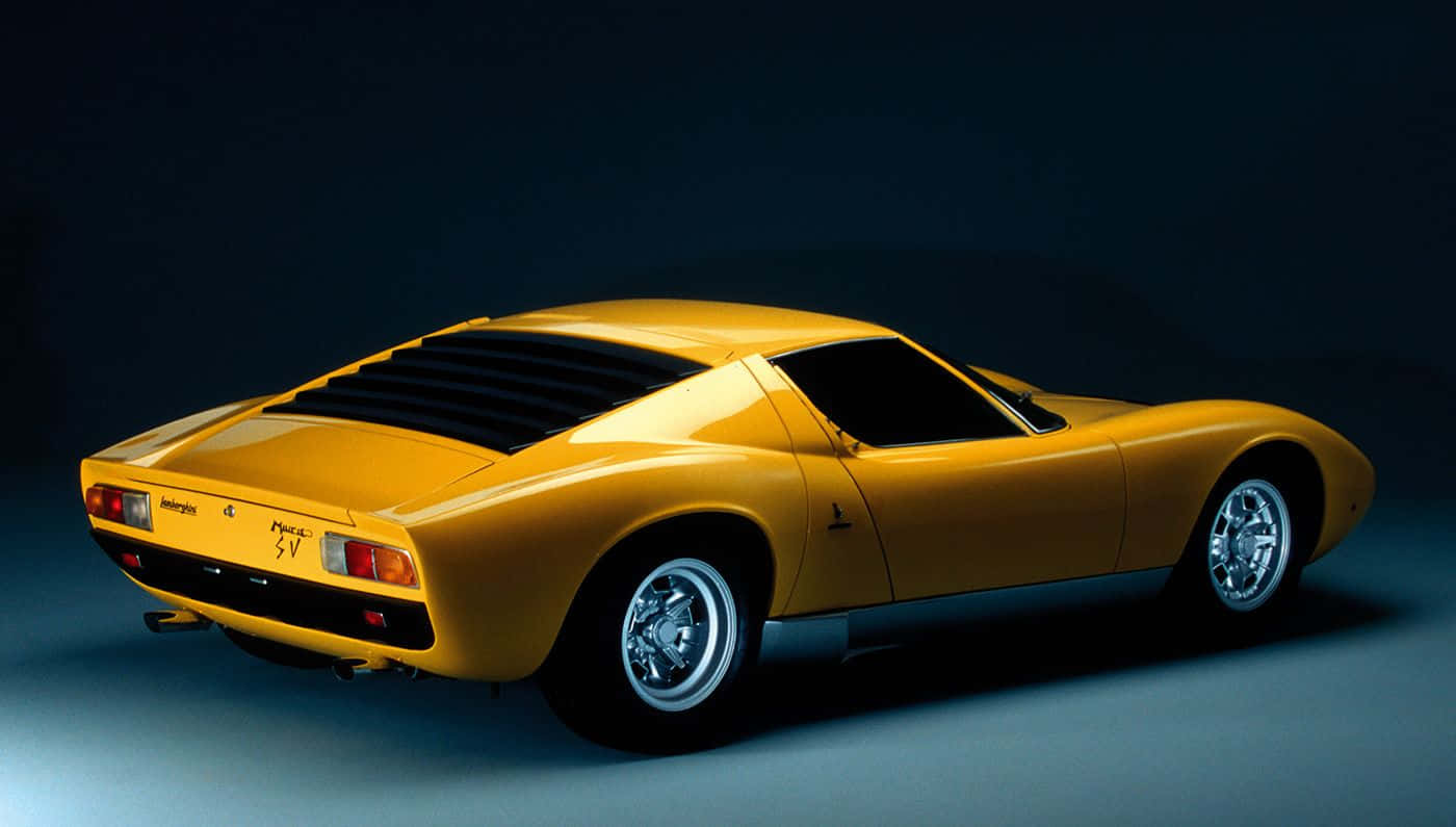 Lamborghini Miura 桌布 壁紙 — 一輛搶眼的黃色藍寶堅尼 Miura SV 跑車在深色背景的攝影棚燈光下閃耀。