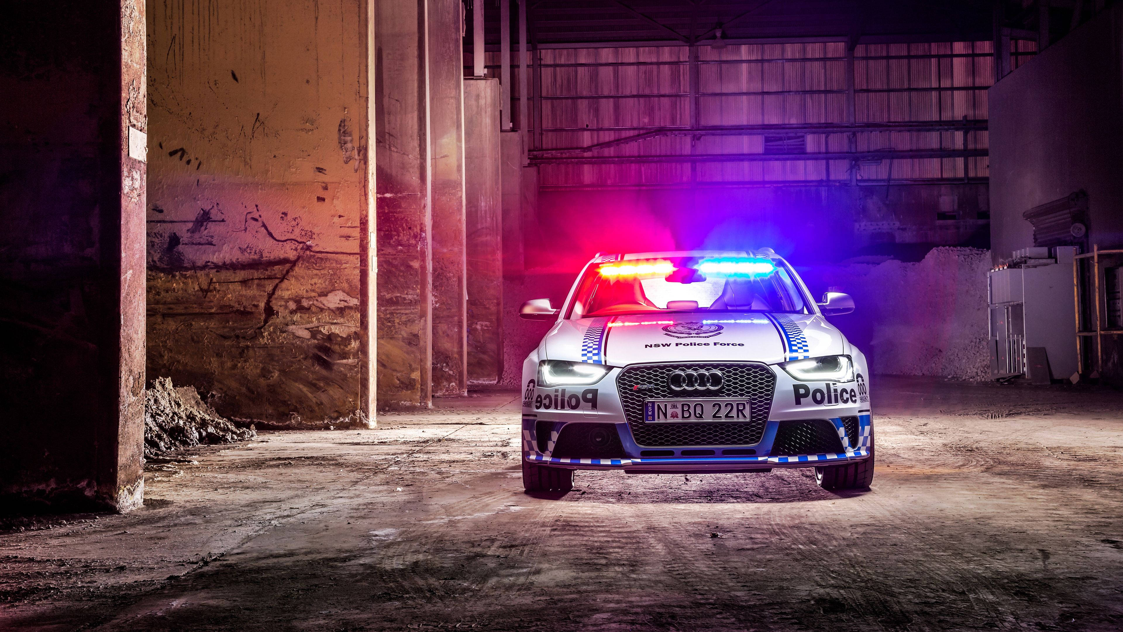 警察 桌布 壁紙 — 一輛新南威爾斯警局的奧迪警車，閃爍著紅藍燈光，停在光線昏暗的廢棄倉庫中。
