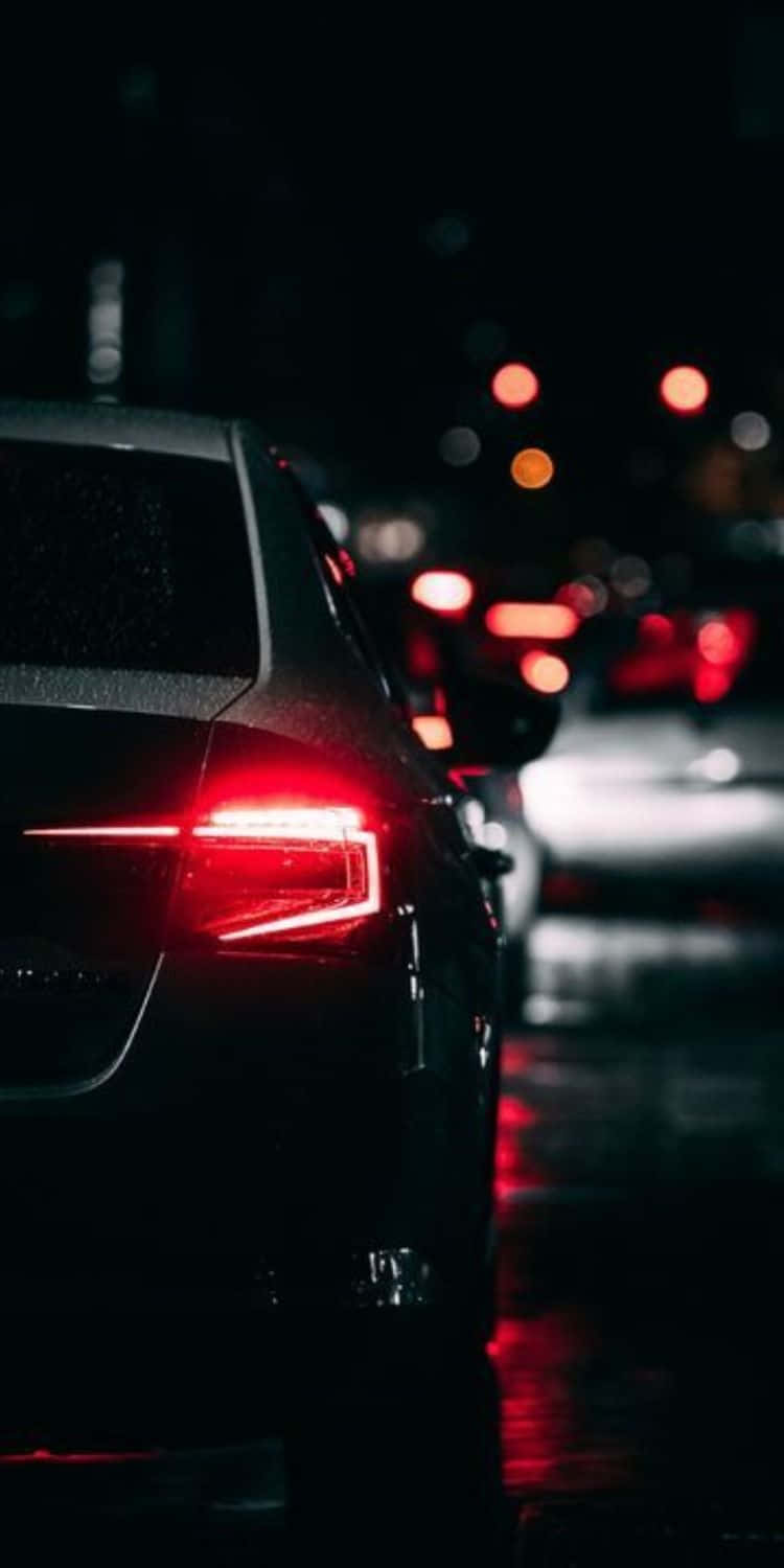 電玩遊戲 桌布 壁紙 — 一輛時尚汽車的紅色尾燈在黑暗夜空下映照在濕漉漉的路面上，城市燈光模糊。