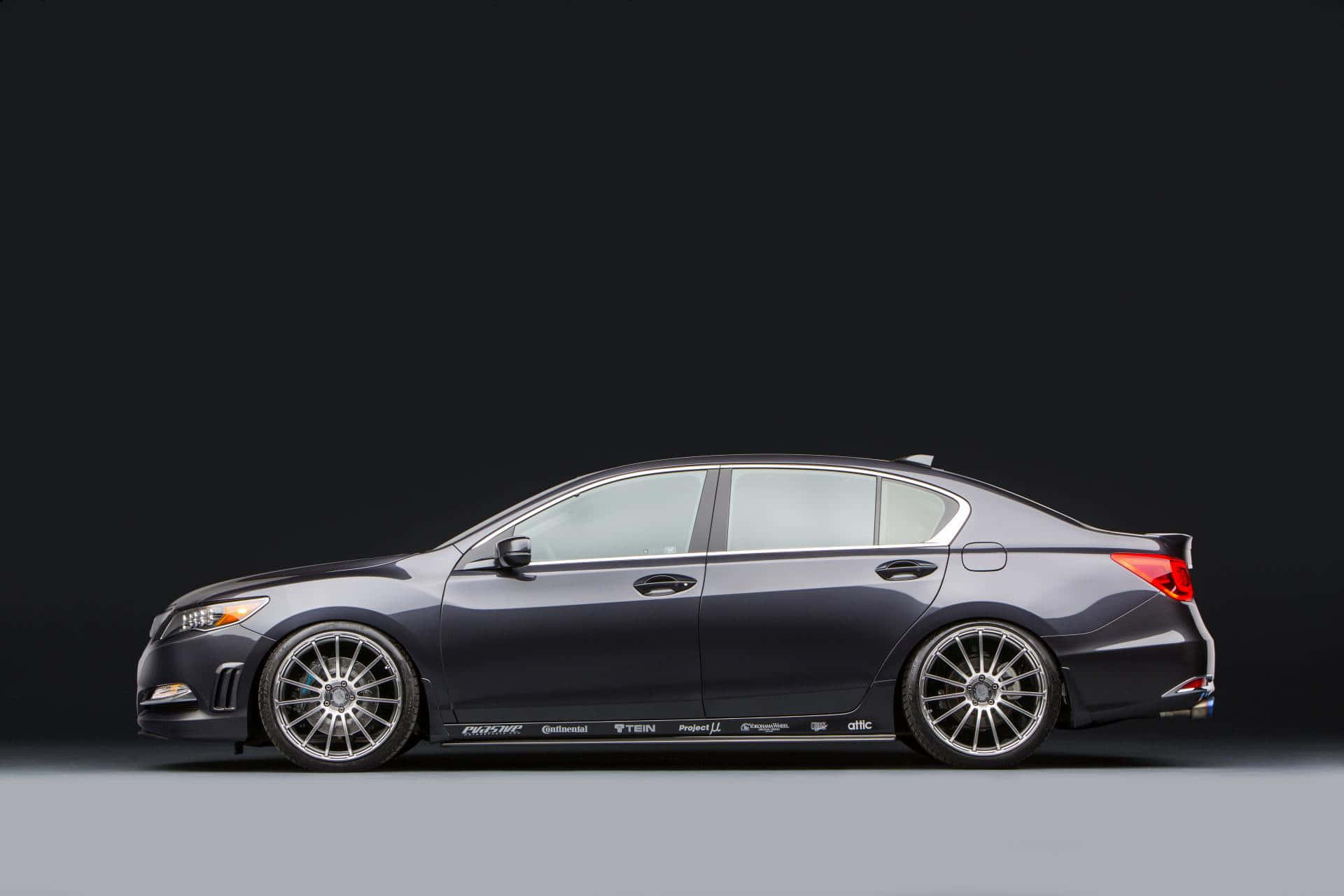 Acura Rlx 桌布 壁紙 — 一輛時尚深灰色改裝轎車，配備訂製輪圈和側面貼紙，以側面輪廓呈現，背景為極簡黑灰工作室背景。