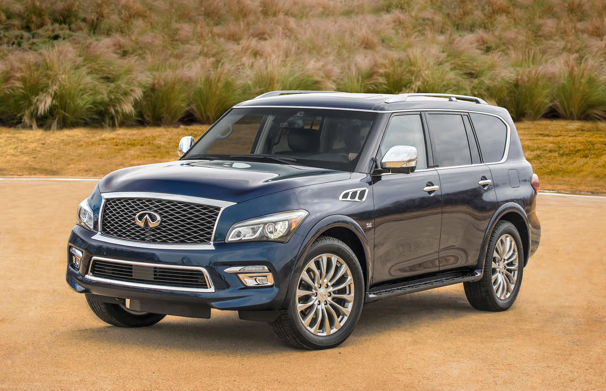 Infiniti Qx80 桌布 壁紙 — 一輛時尚深藍色 Infiniti QX80 SUV 停泊在泥路上，背景是乾燥的草坡。
