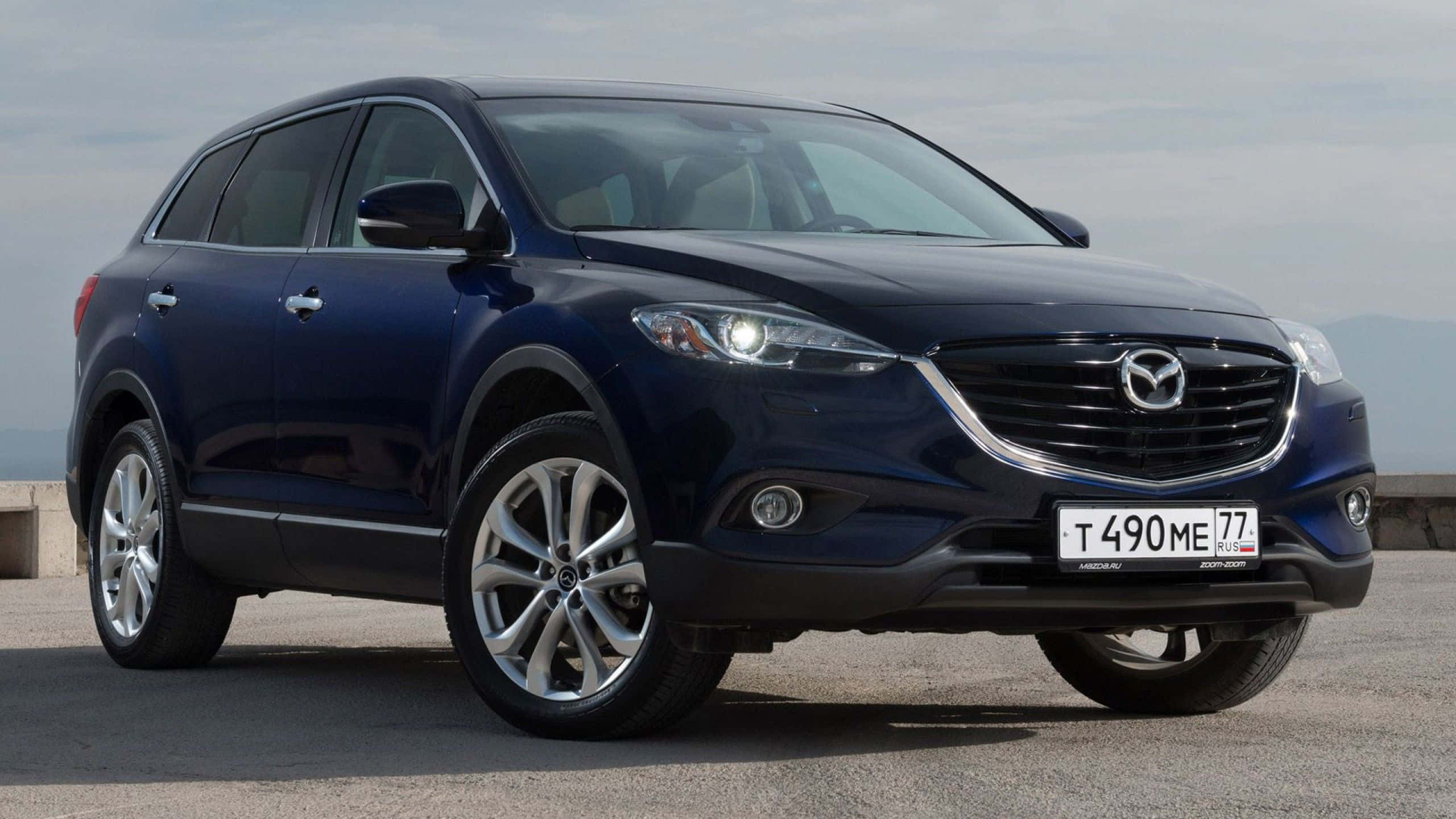 Mazda Cx-9 桌布 壁紙 — 一輛時尚深藍色Mazda CX-9 SUV停放在混凝土表面上，遠山在陰天天空下。