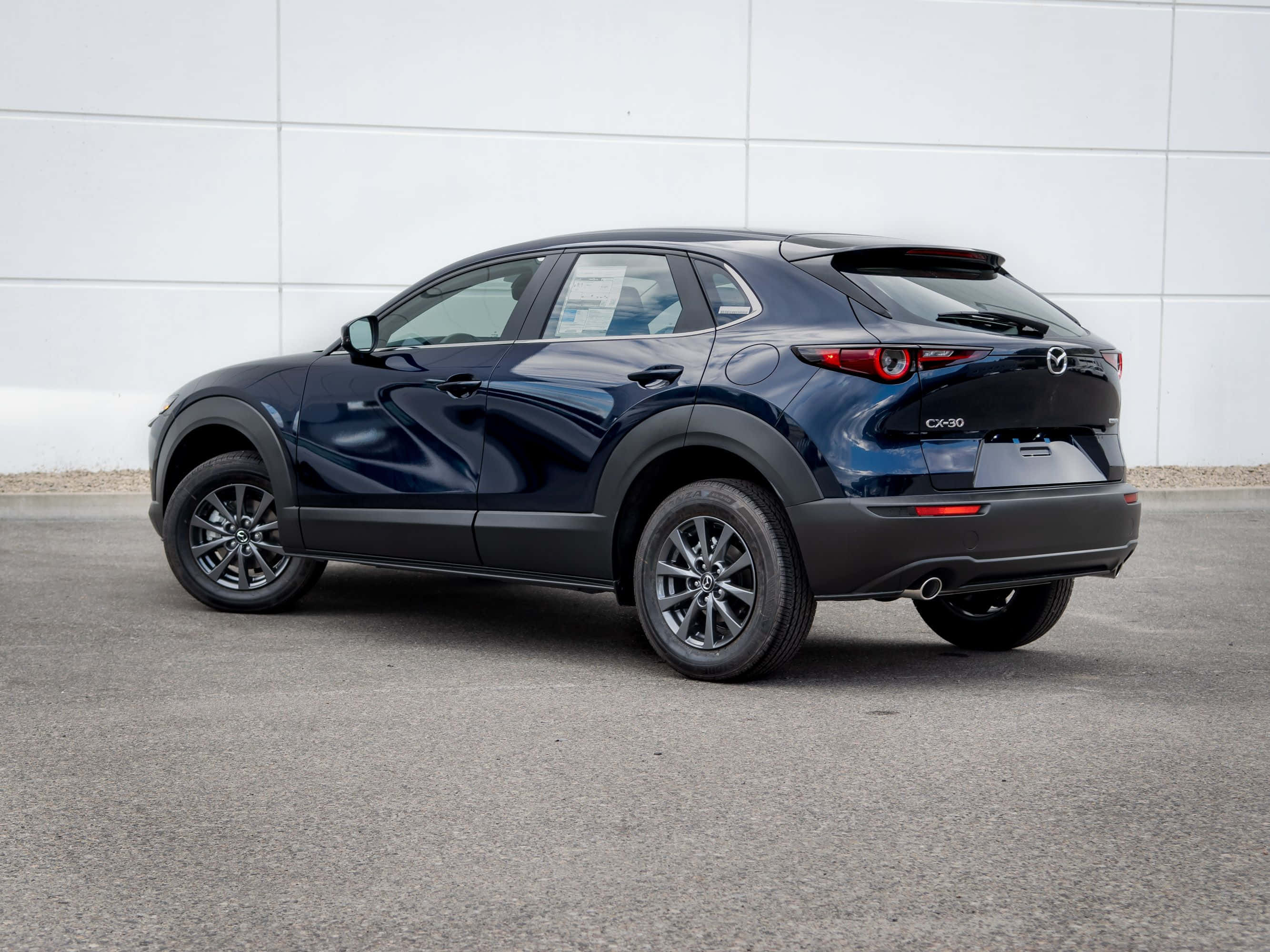 Mazda Cx-30 桌布 壁紙 — 一輛時尚深藍色Mazda CX-30 SUV停泊在瀝青路上，背景是簡約的白色瓷磚牆。