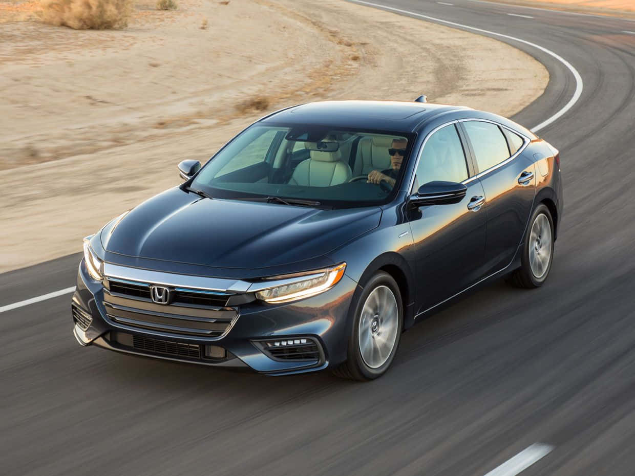 Honda Insight 桌布 壁紙 — 一輛時尚深藍色本田轎車在溫暖金色陽光下，沿著蜿蜒的沙漠高速公路奔馳。
