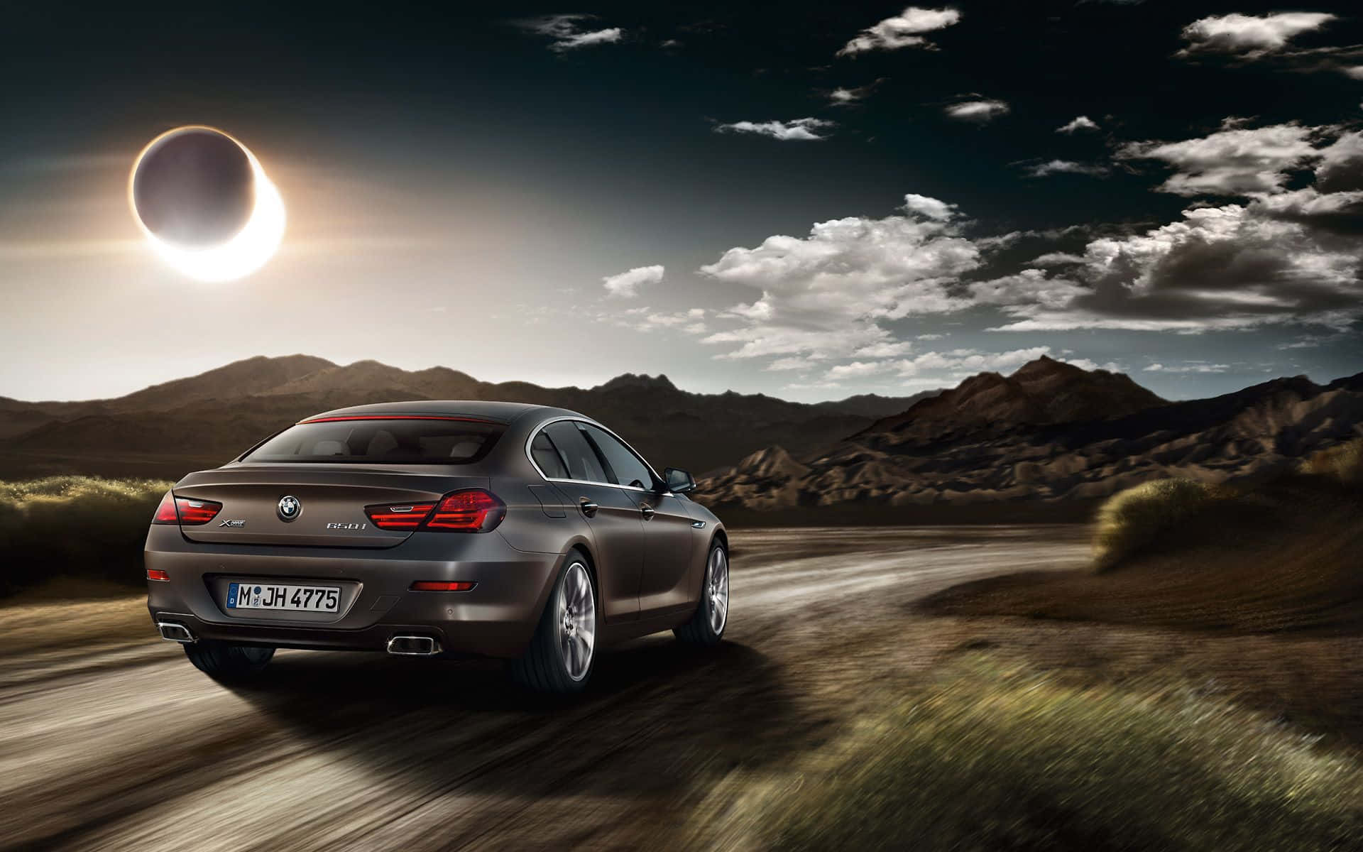 Bmw 6 Series 桌布 壁紙 — 一輛時尚灰色BMW 6系列在沙漠公路上行駛，背景是戲劇性的日食和崎嶇的山脈。
