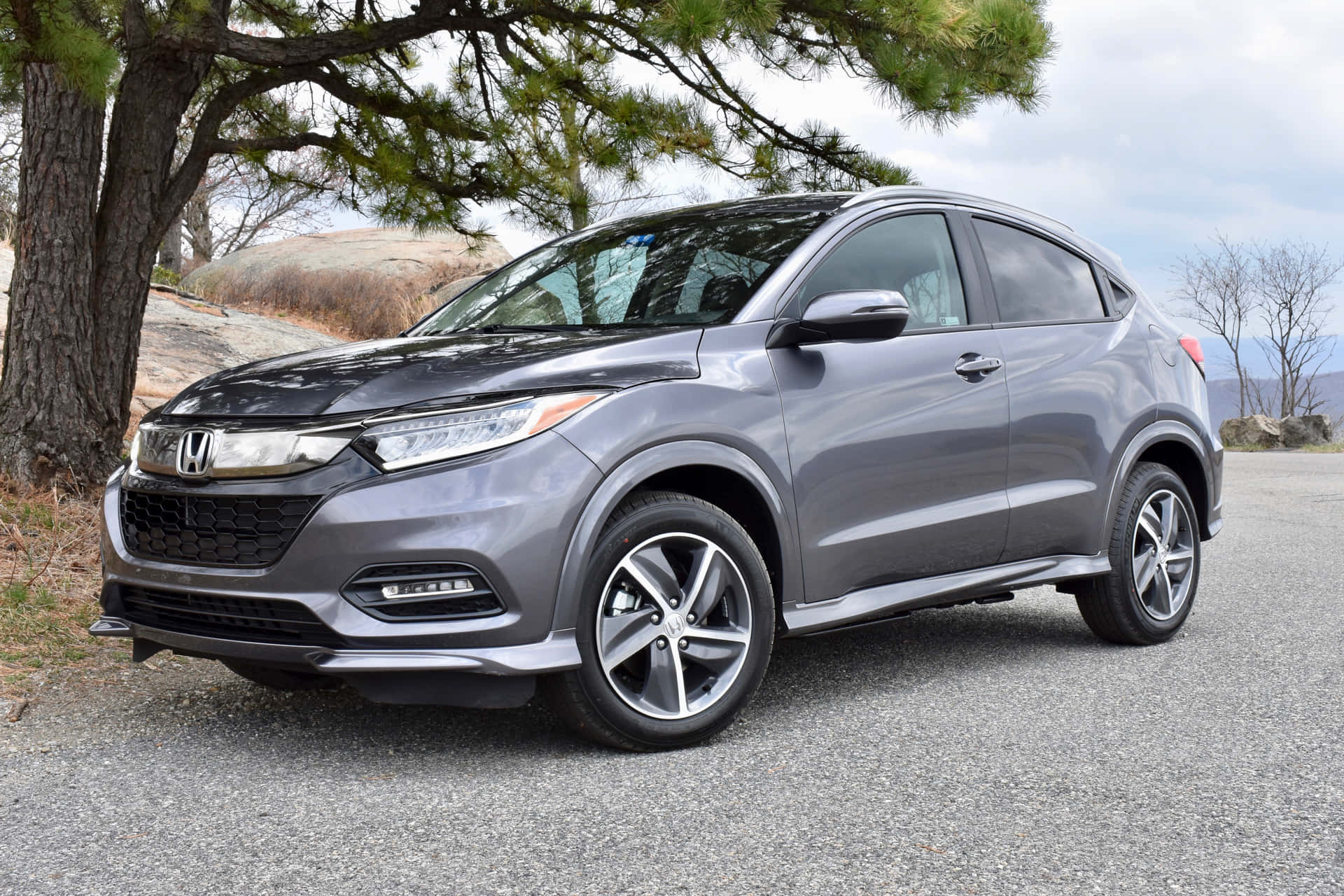Honda Hr-v 桌布 壁紙 — 一輛時尚灰色本田 HR-V SUV 停泊在松樹下的碎石路上，背景是岩石丘陵。