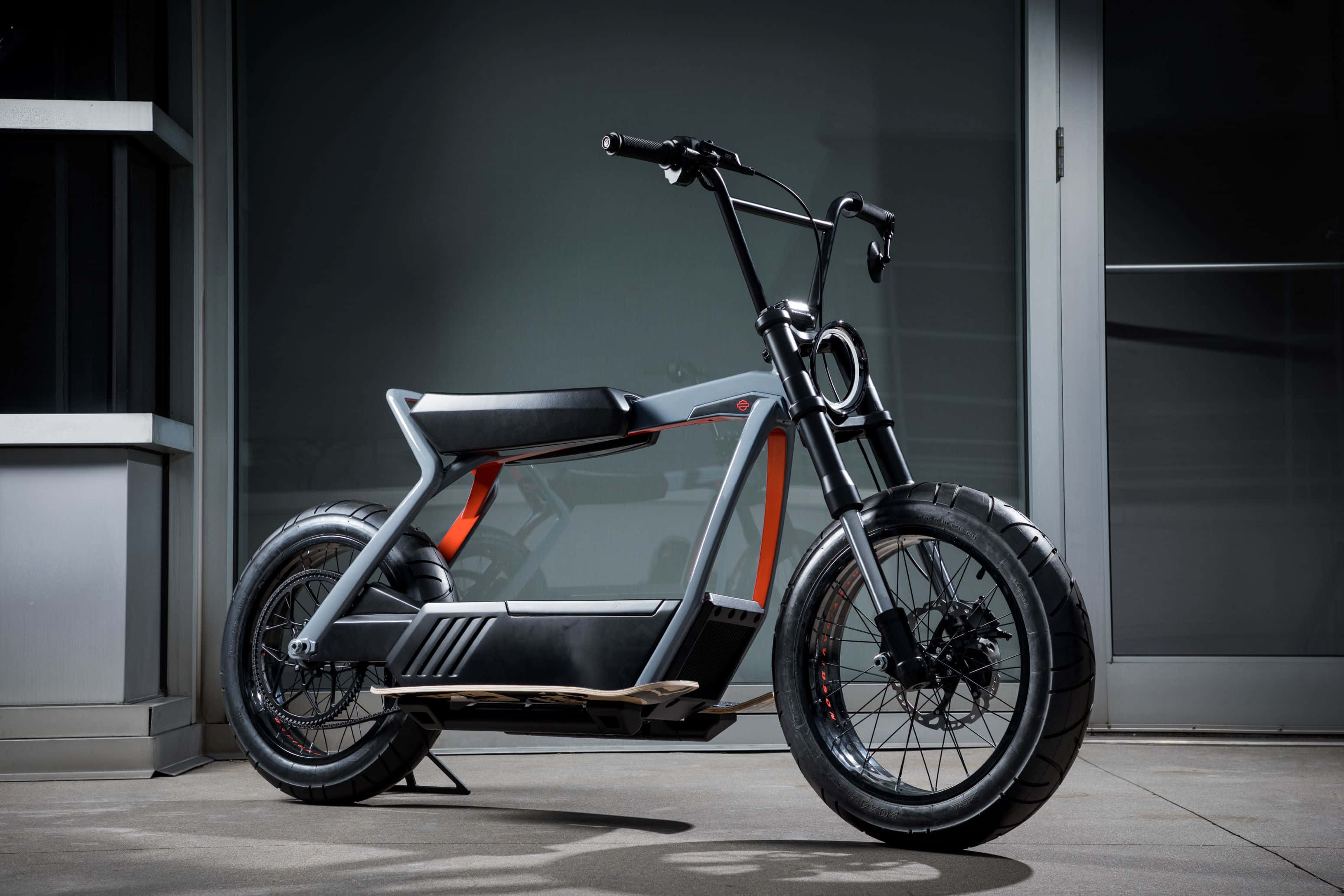 Electric Bike 桌布 壁紙 — 一輛時尚現代電動自行車帶有醒目橙色點綴，停放在極簡城市建築外牆前。