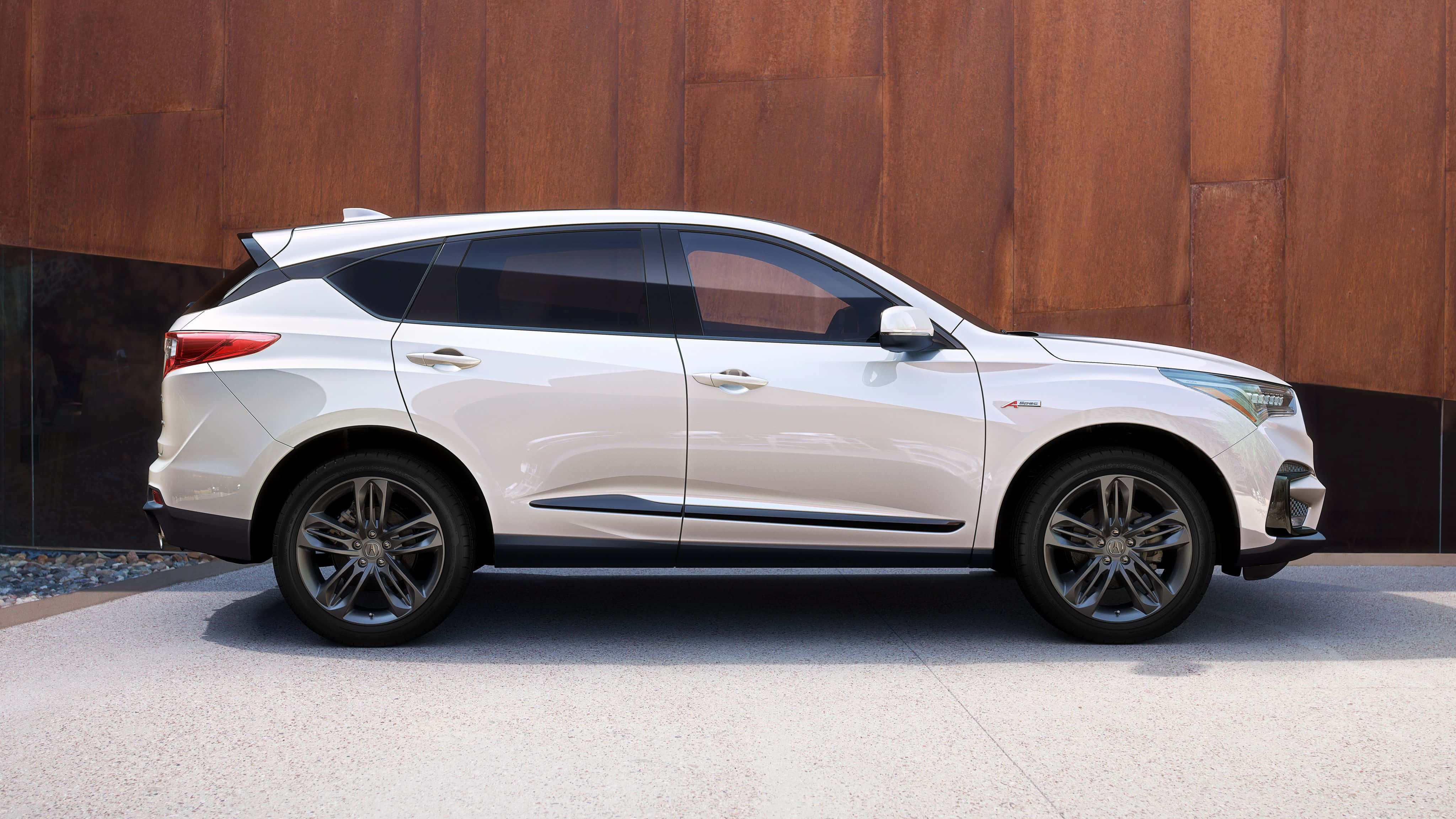 Acura Rdx 桌布 壁紙 — 一輛時尚白色SUV在明亮日光下停靠在帶紋理的鏽色牆邊。
