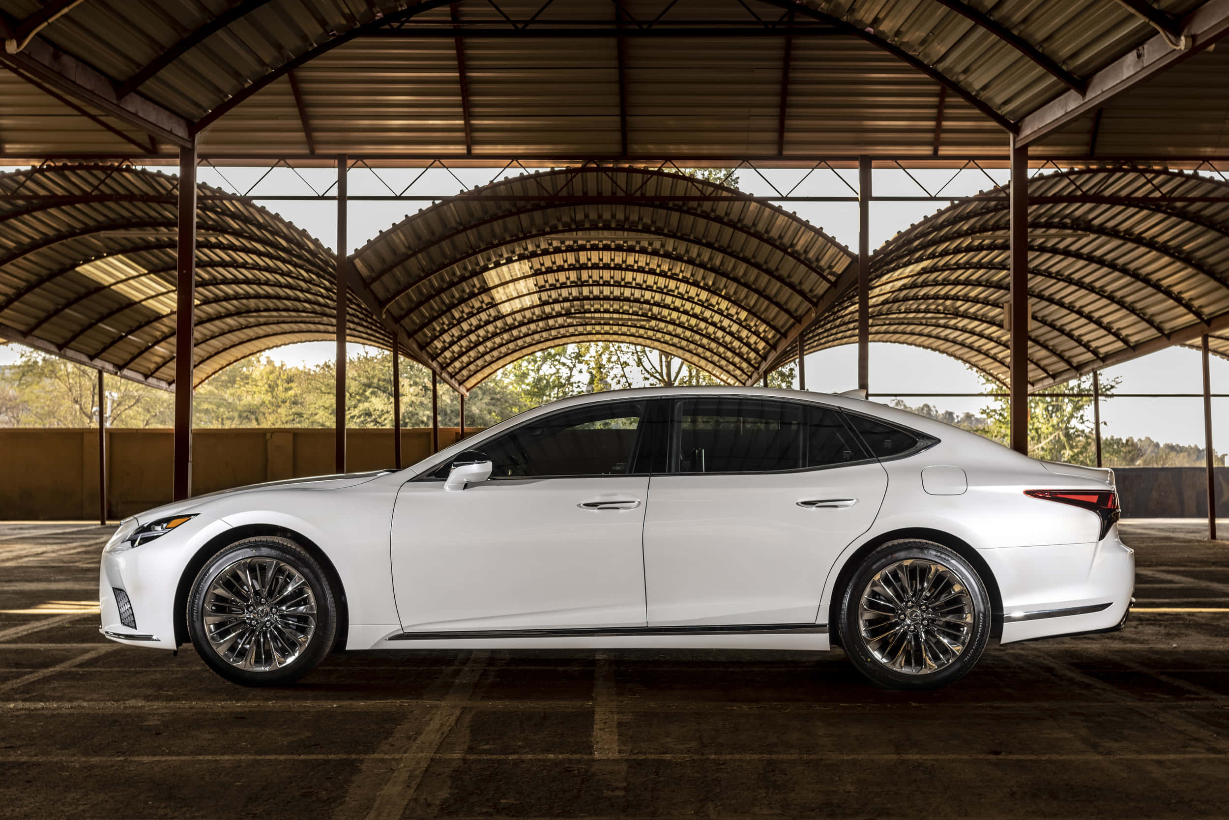 Lexus Ls 500 桌布 壁紙 — 一輛時尚白色豪華轎車停放在彎曲金屬屋頂下，陽光穿透灑落。