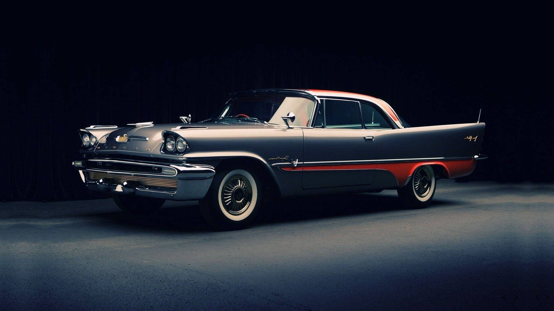 經典汽車 桌布 壁紙 — 一輛時尚的1950年代雪佛蘭，帶有鍍鉻裝飾和紅色飾邊，在戲劇性的工作室燈光下，在黑暗背景下閃耀。