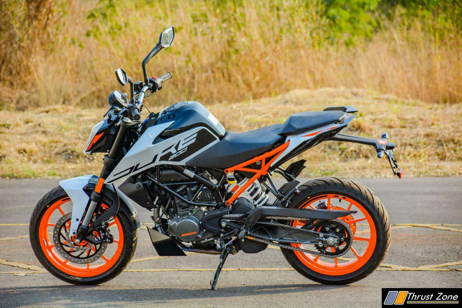 KTM 摩托車 桌布 壁紙 — 一輛時尚的KTM Duke 200機車，配以鮮豔橙色車輪和黑色點綴，停放在乾草旁的柏油路上。