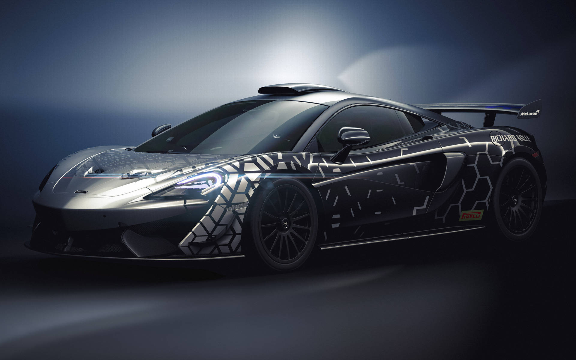 Auto Racing 桌布 壁紙 — 一輛時尚的McLaren跑車，帶有黑色和銀色的幾何圖案塗裝，在戲劇性的工作室燈光下閃耀。