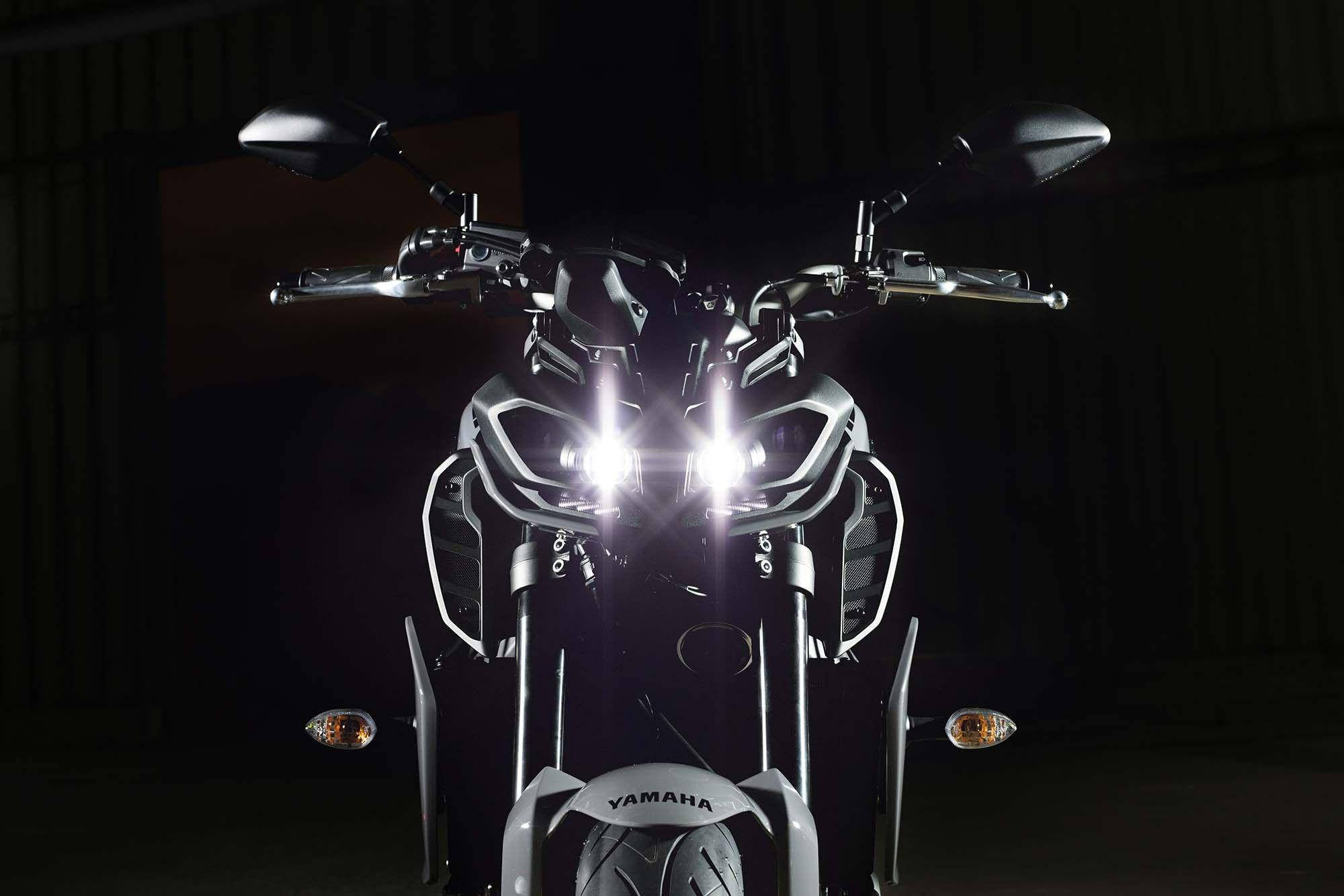 yamaha mt 15 桌布 壁紙 — 一輛時尚的Yamaha摩托車的發光頭燈在戲劇性的攝影棚拍攝中刺穿黑暗。