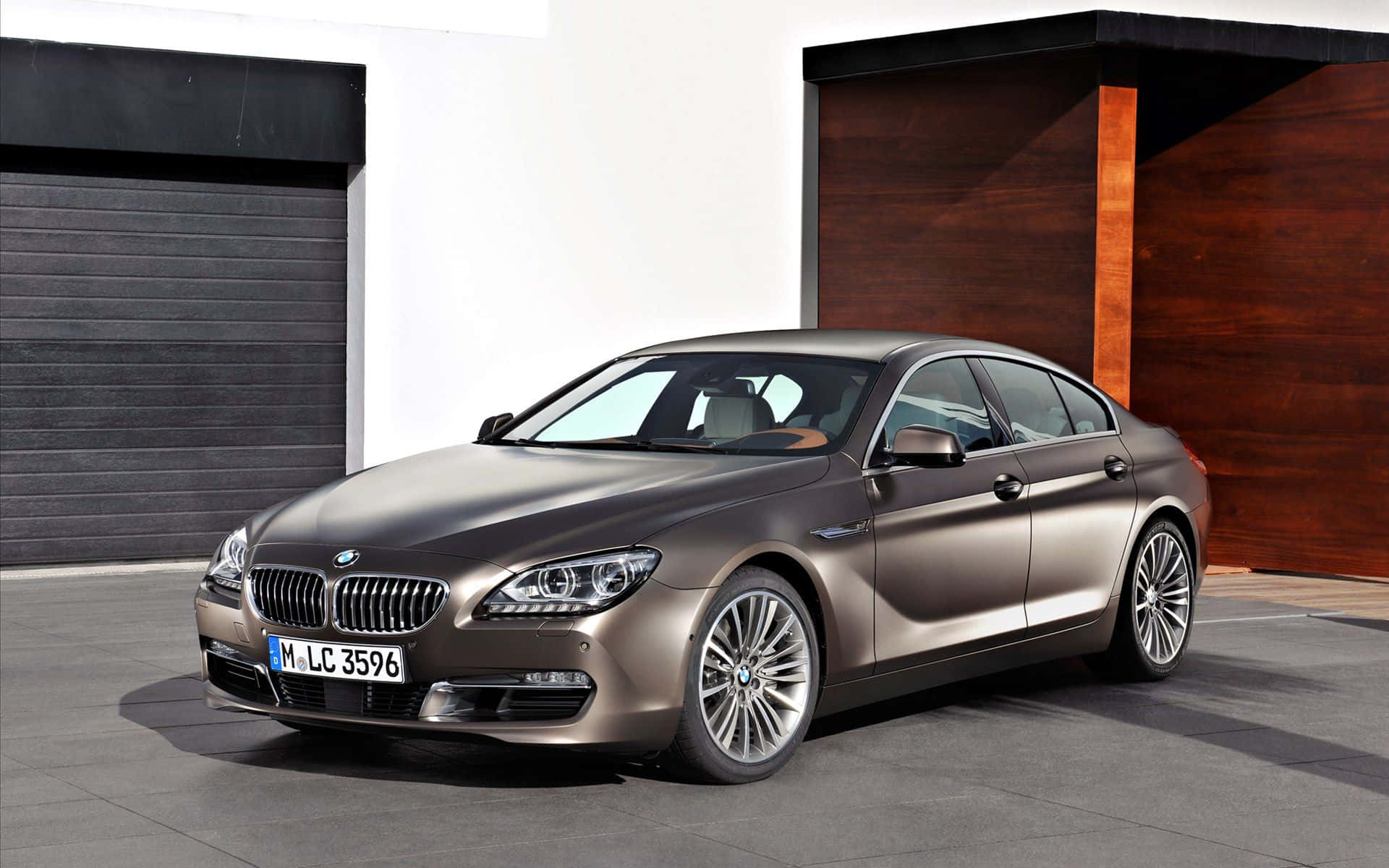 Bmw 6 Series 桌布 壁紙 — 一輛時尚的啞光棕色BMW 6系列轎車停放在現代簡約車庫中，配有深色木材和白色牆壁。